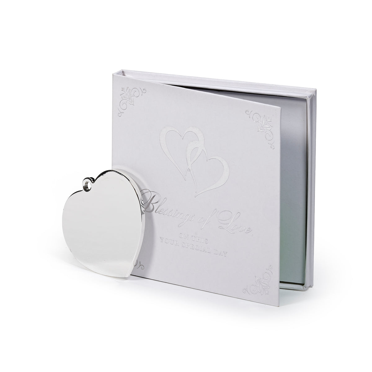Rear view of heart ornament showing its plain silver-toned back beside the gift packaging.