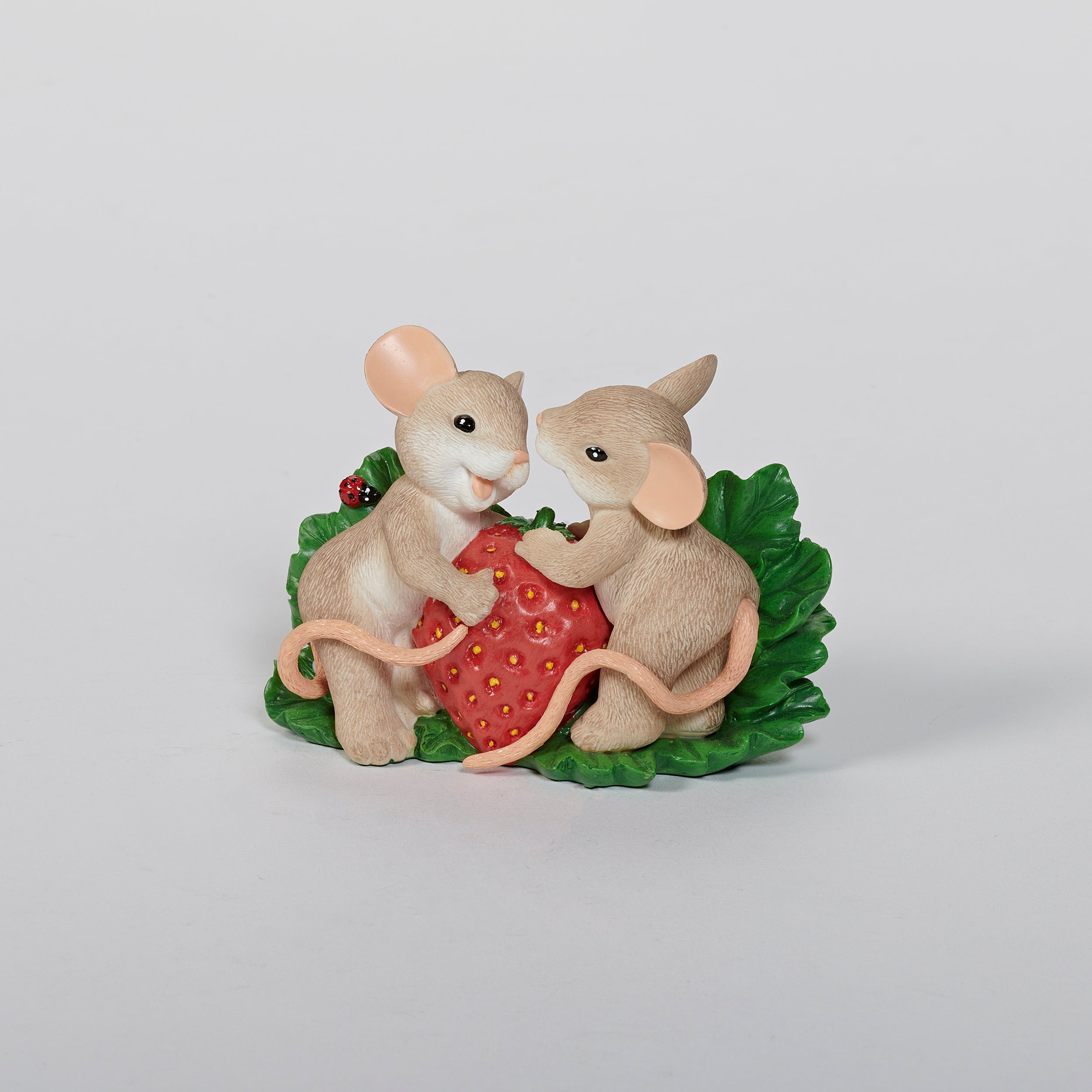 Two mouse figurines holding a strawberry