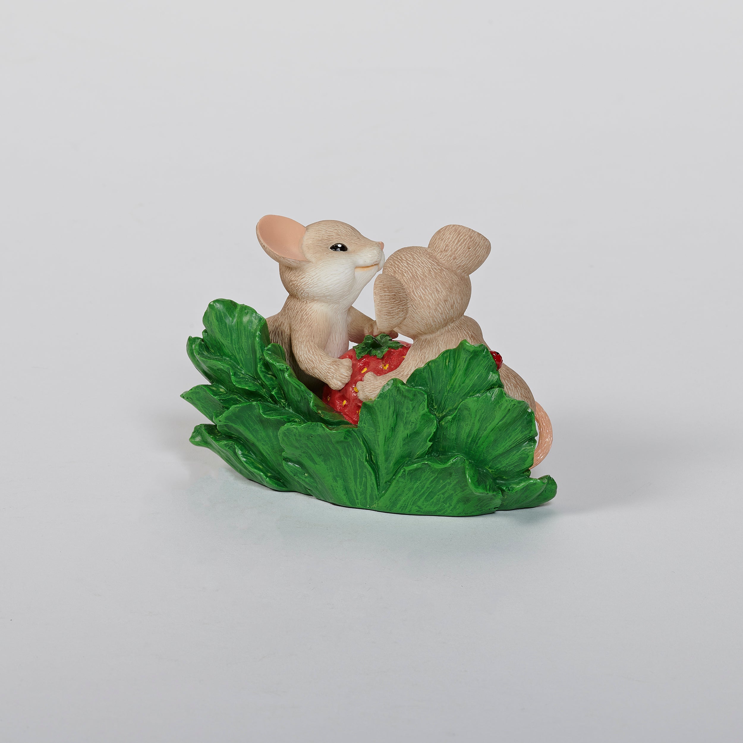 Two mouse figurines holding a strawberry