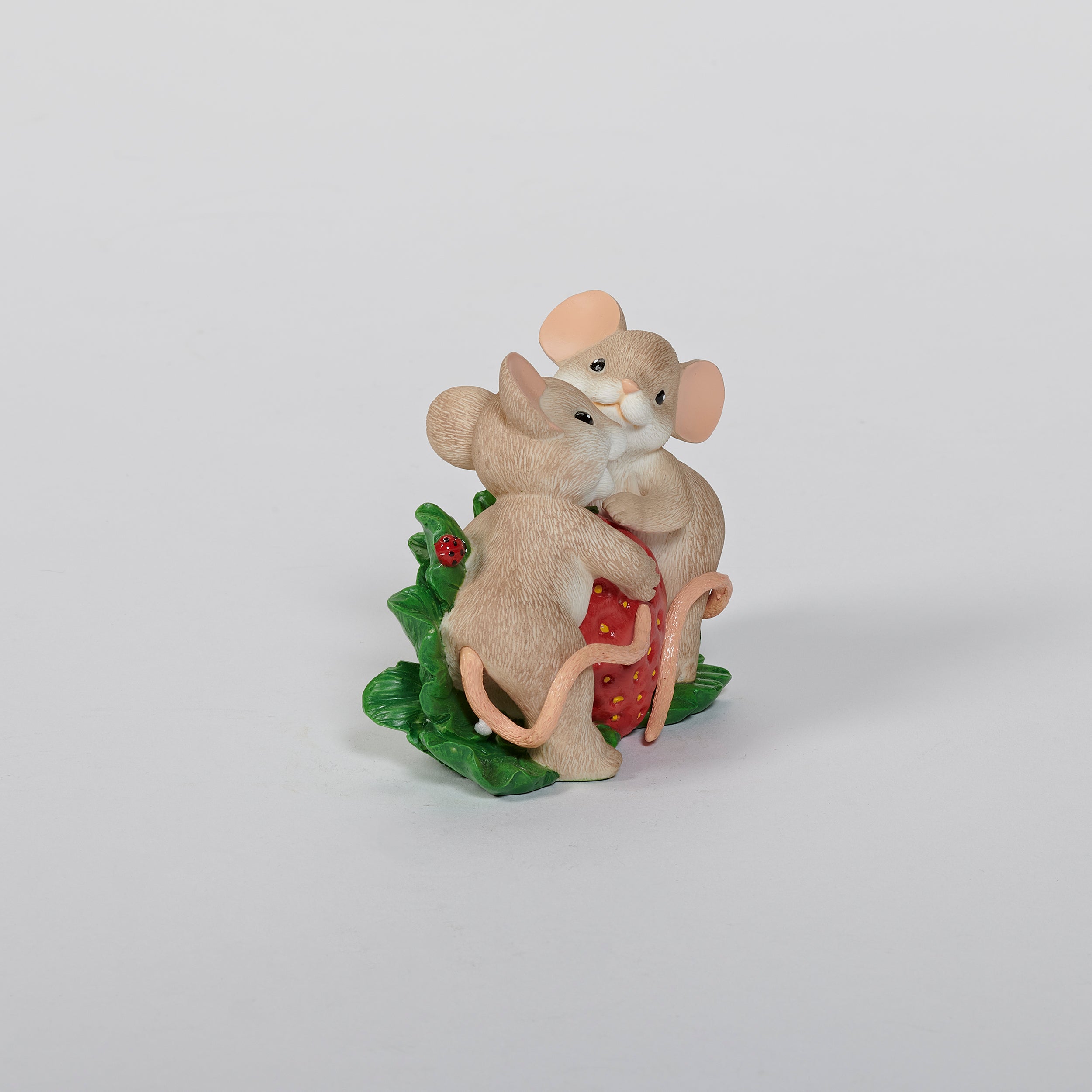 Two mouse figurines holding a strawberry