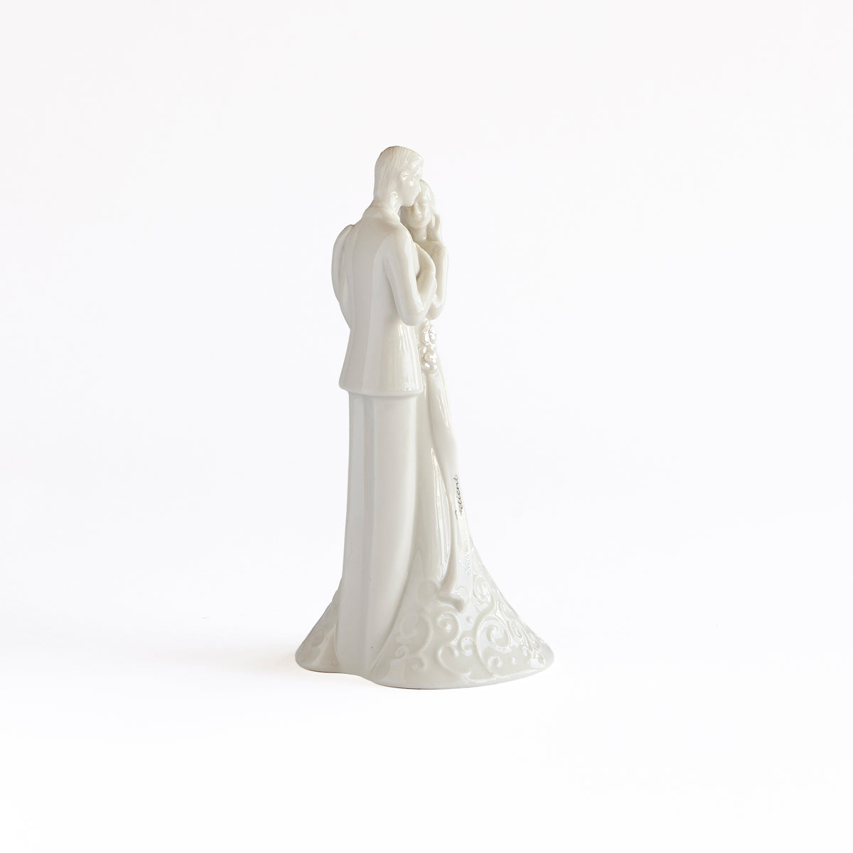 Rear view of porcelain bride and groom showing the gown’s trailing shape and the groom’s suit.
