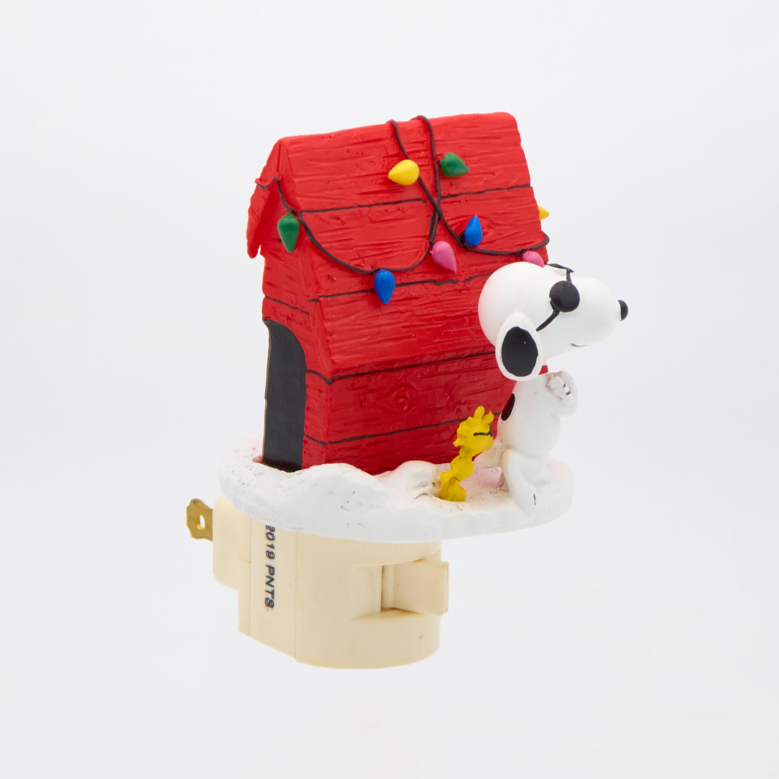 Decorative night light with Snoopy and Woodstock in front of a red dpg house with Christmas lights.