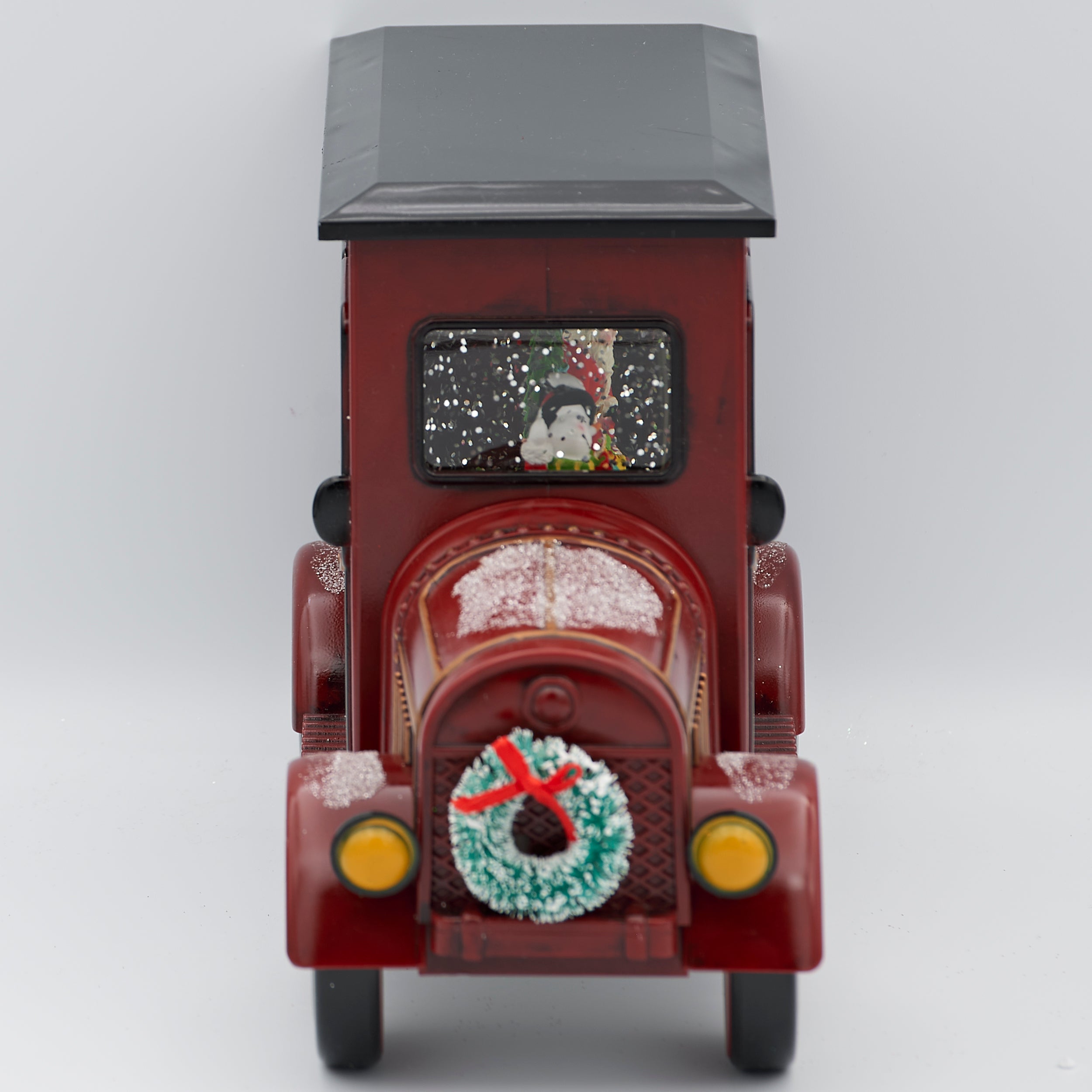 Decorative model of a vintage car with a Christmas wreath on a white background