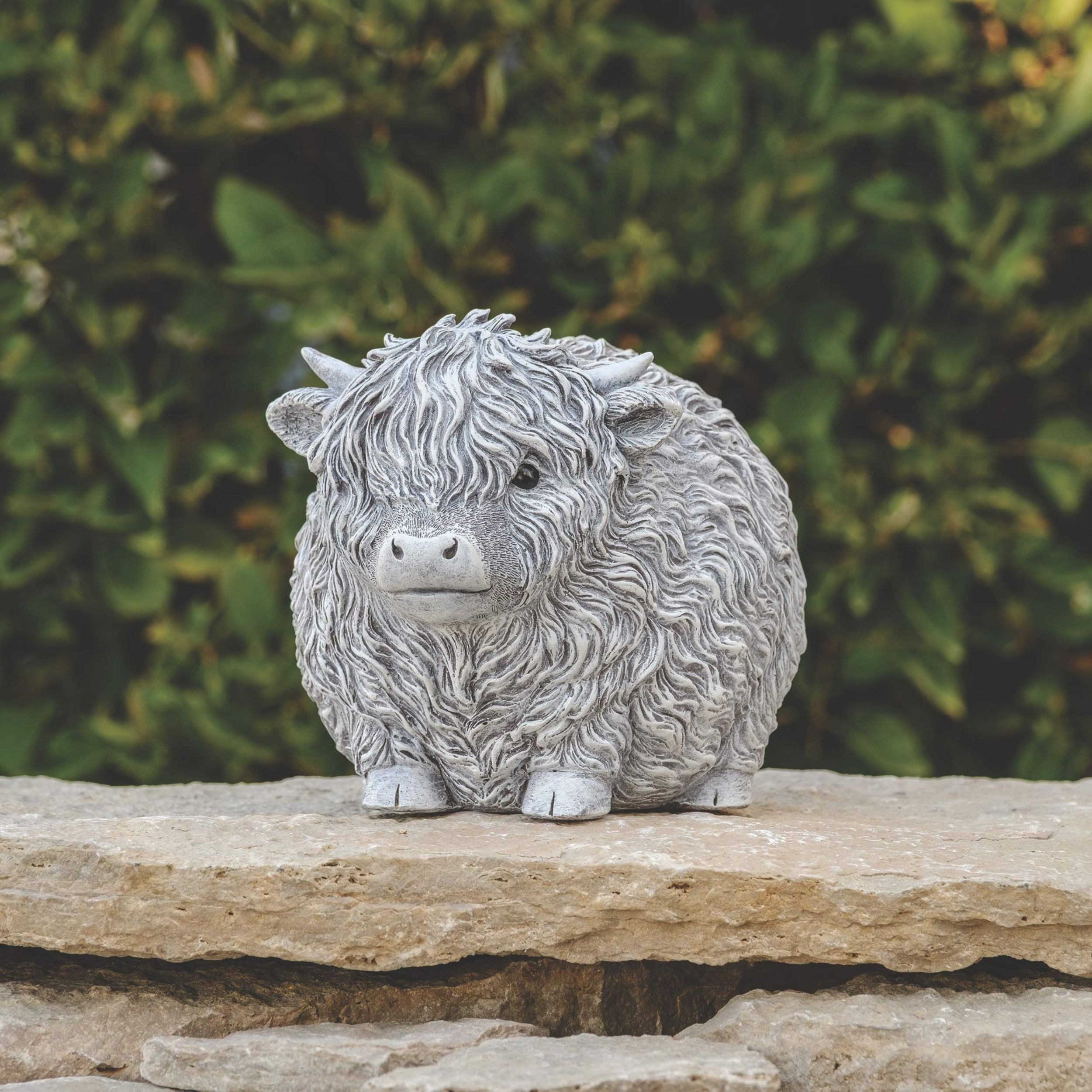 Statue of a fluffy animal on a stone surface with a blurred green background