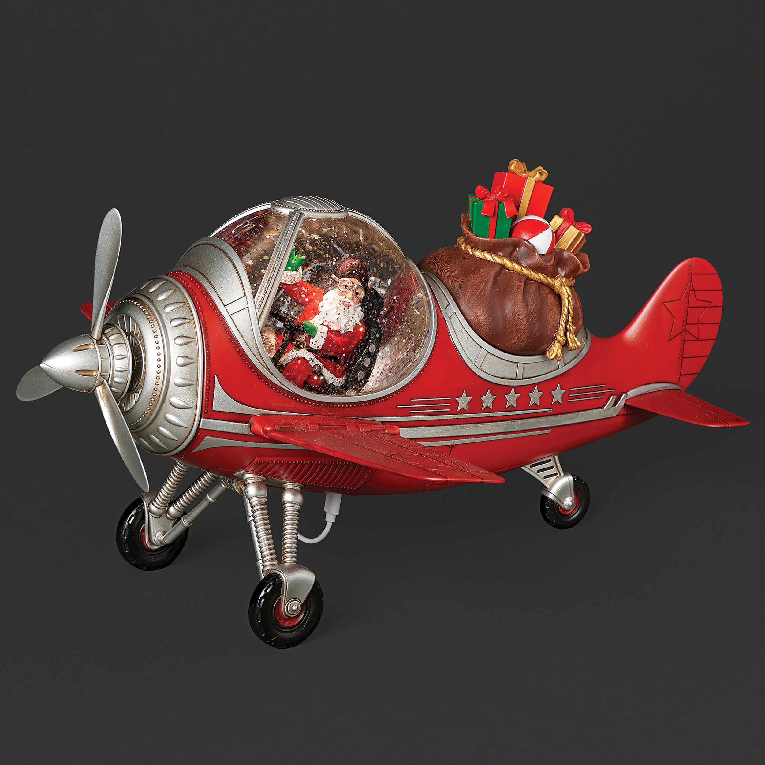 Red airplane-shaped snowglobe with Santa Claus and gifts on a dark background