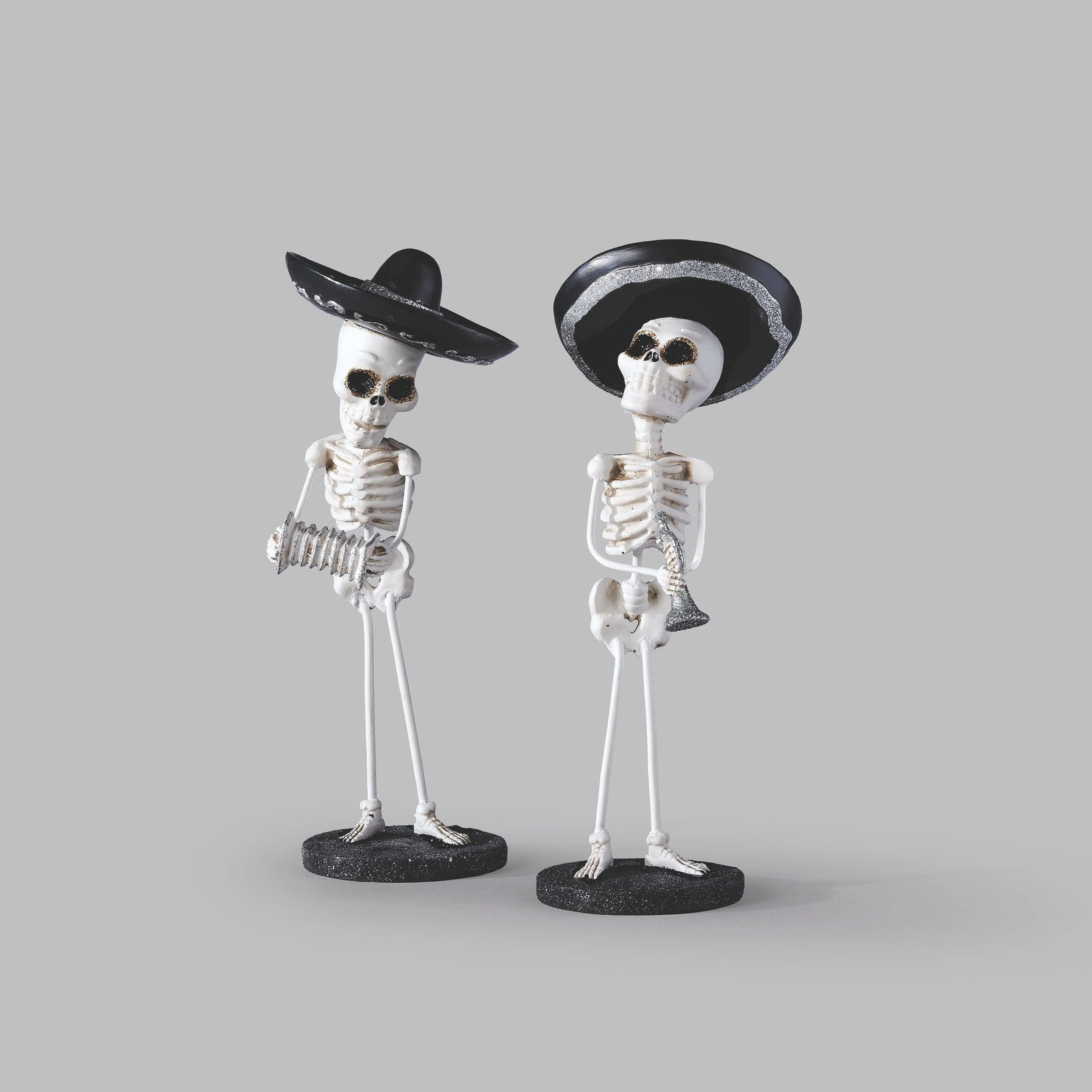 Two skeleton figures wearing sombreros on a gray background