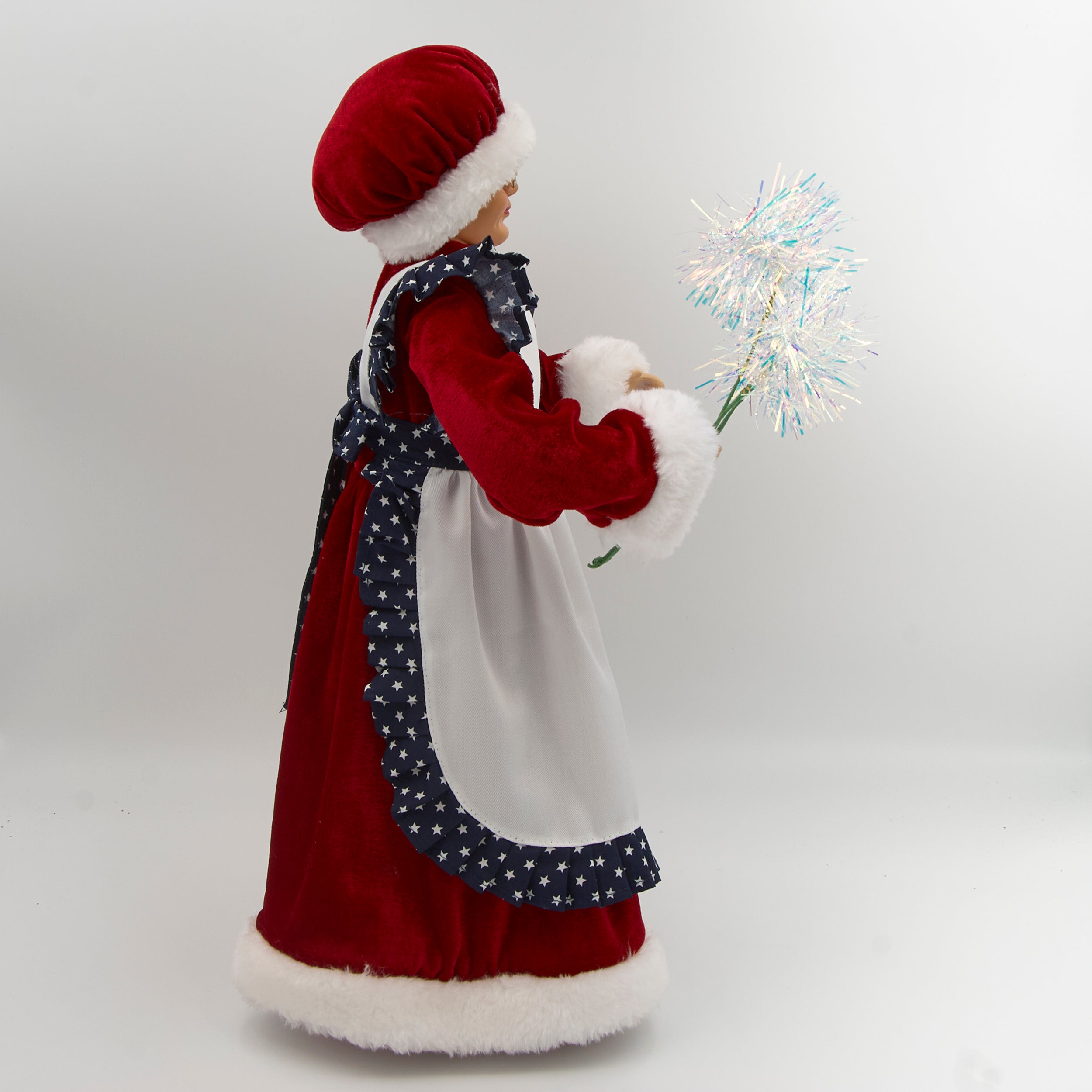 Decorative figure of a woman in a traditional outfit with a white apron and red hat, holding sparklers on a white background.