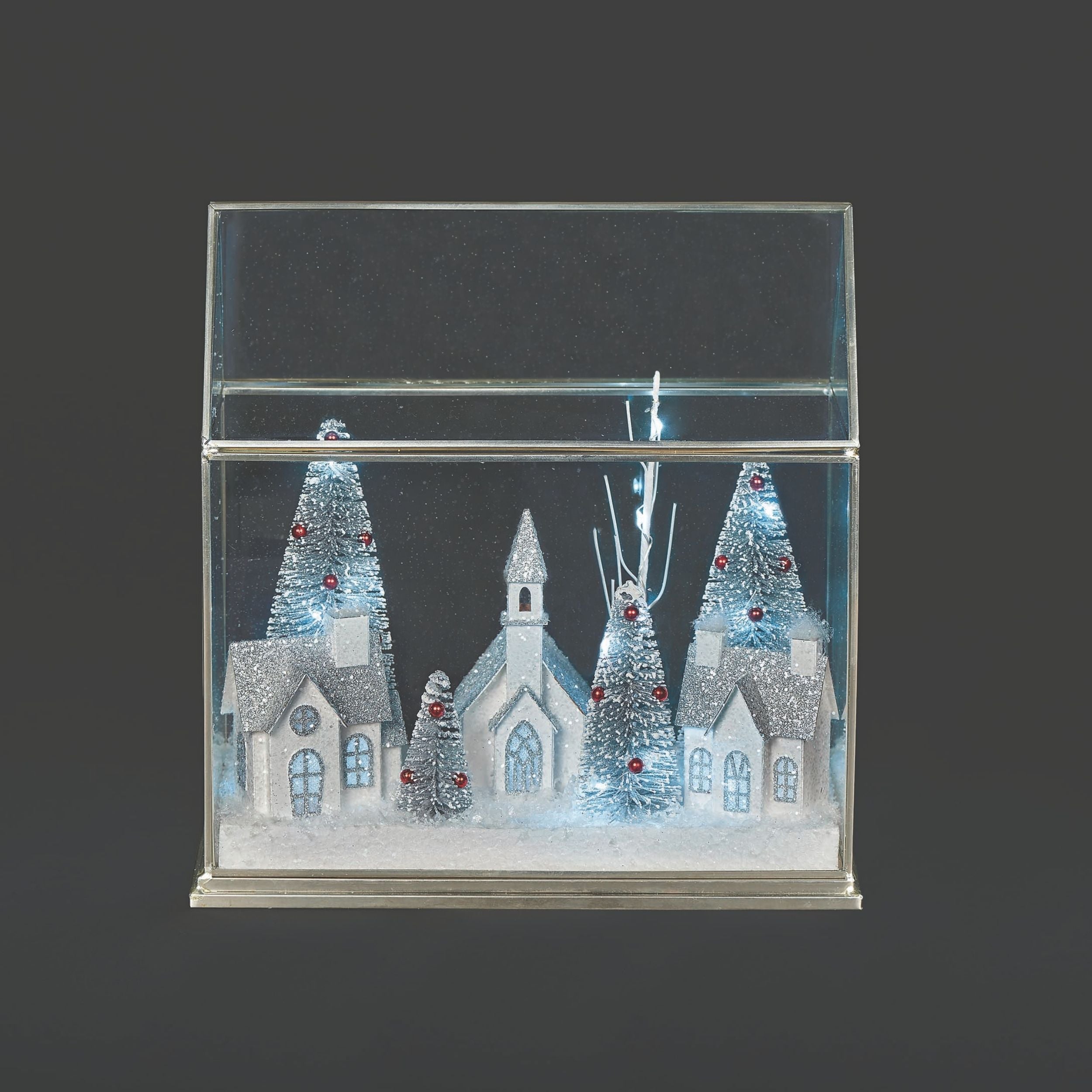 Decorative glass box with a winter scene featuring trees and buildings on a black background
