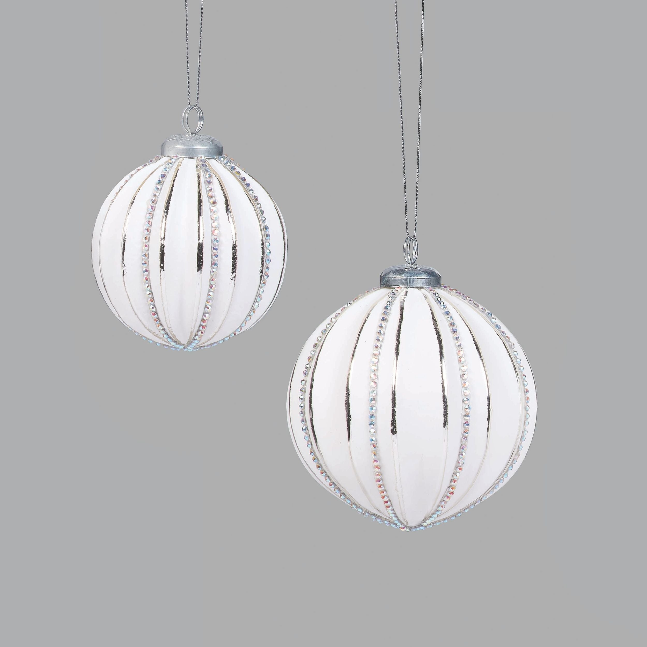 Two white spherical ornaments with decorative elements on a light gray background