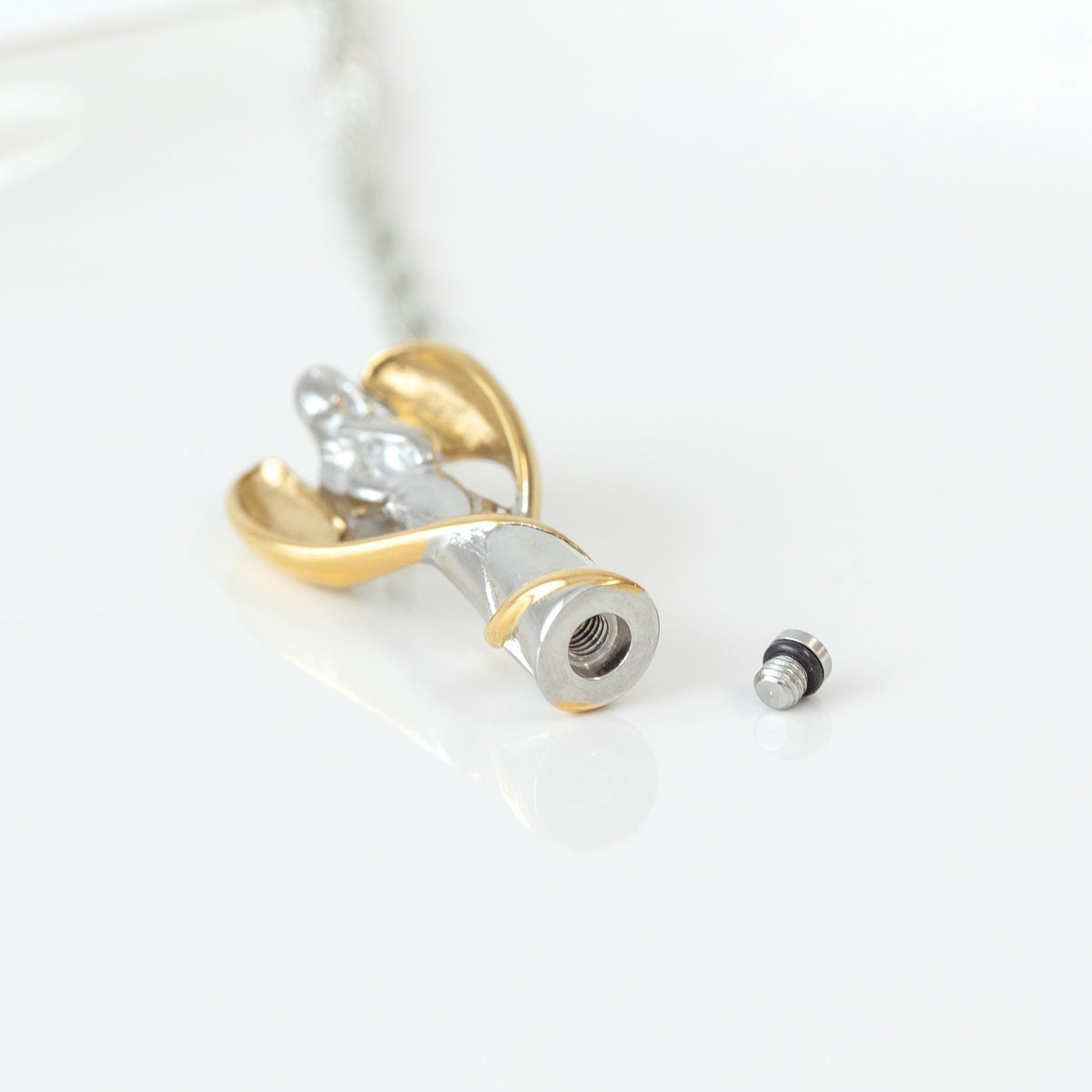 Guardian angel memorial urn necklace showing removable screw closure for holding a small portion of ashes