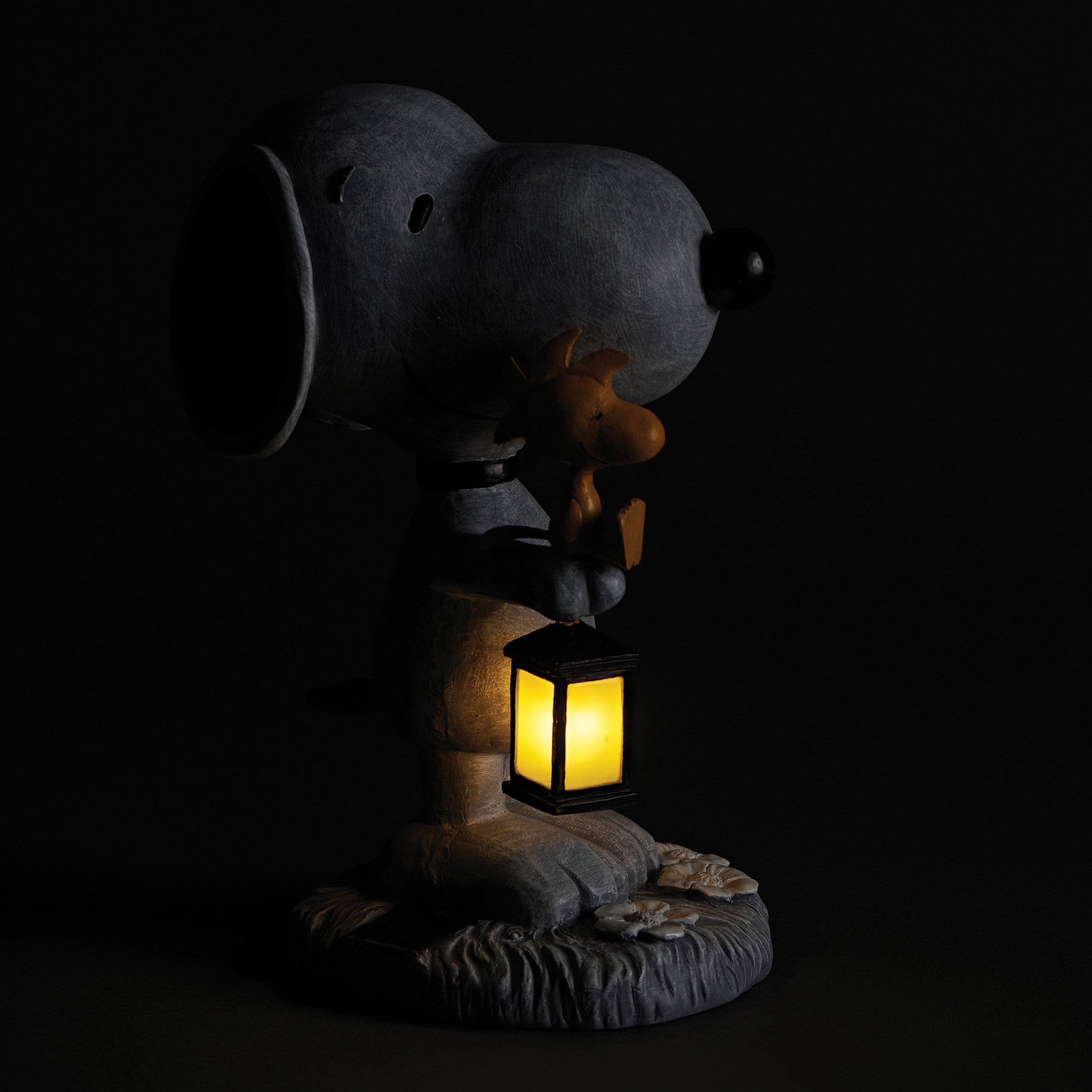 Snoopy holding woodstock and a solar lantern in the dark