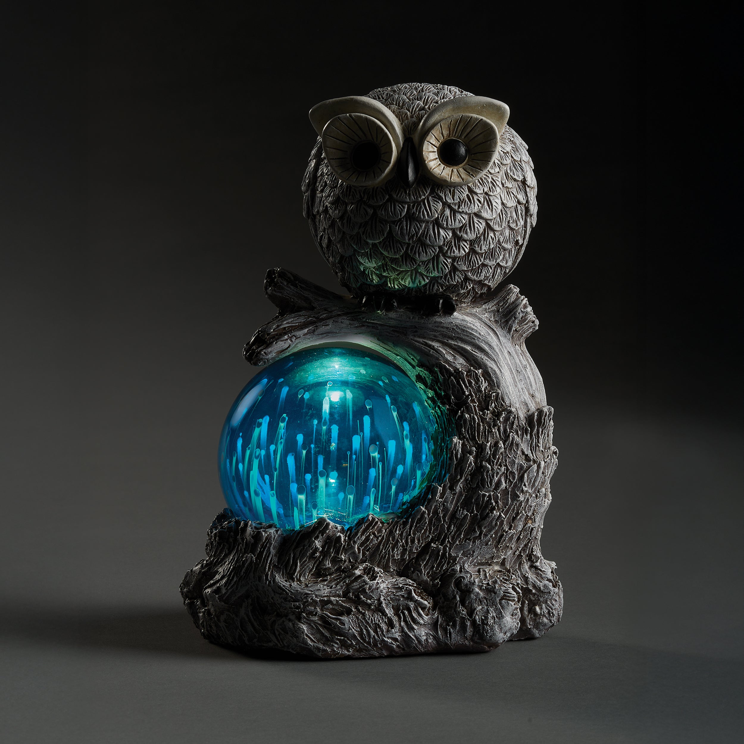 Decorative owl sculpture with a blue solar dome in the dark