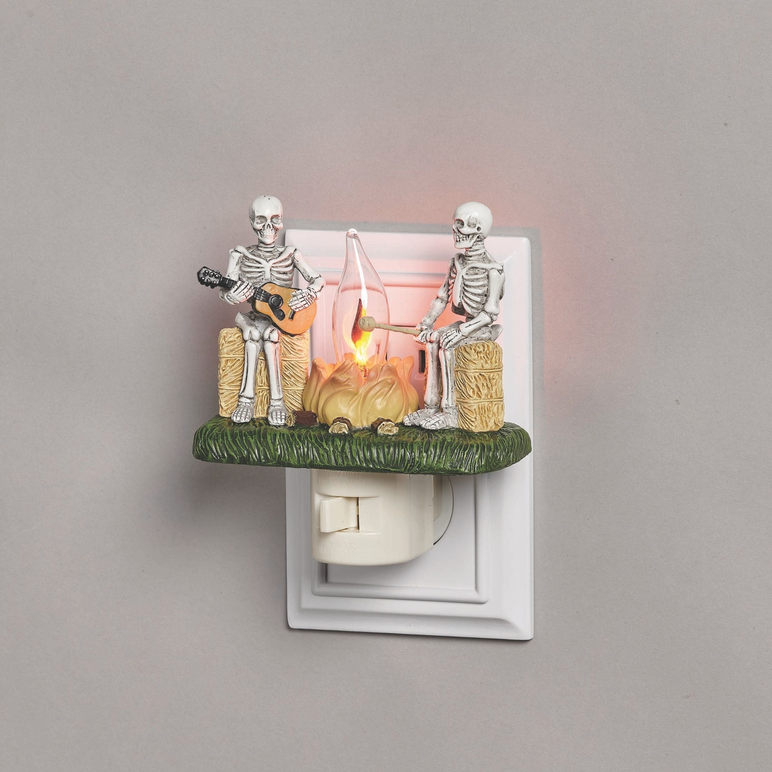 Decorative night light with skeletons playing music on a gray background