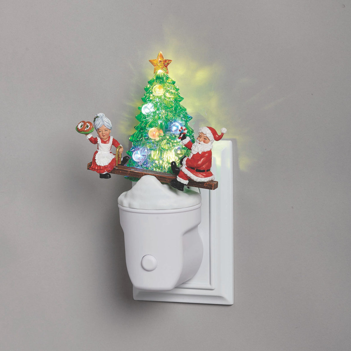 Decorative night light with Santa Claus and Mrs. Claus figures and a Christmas tree on a gray background.