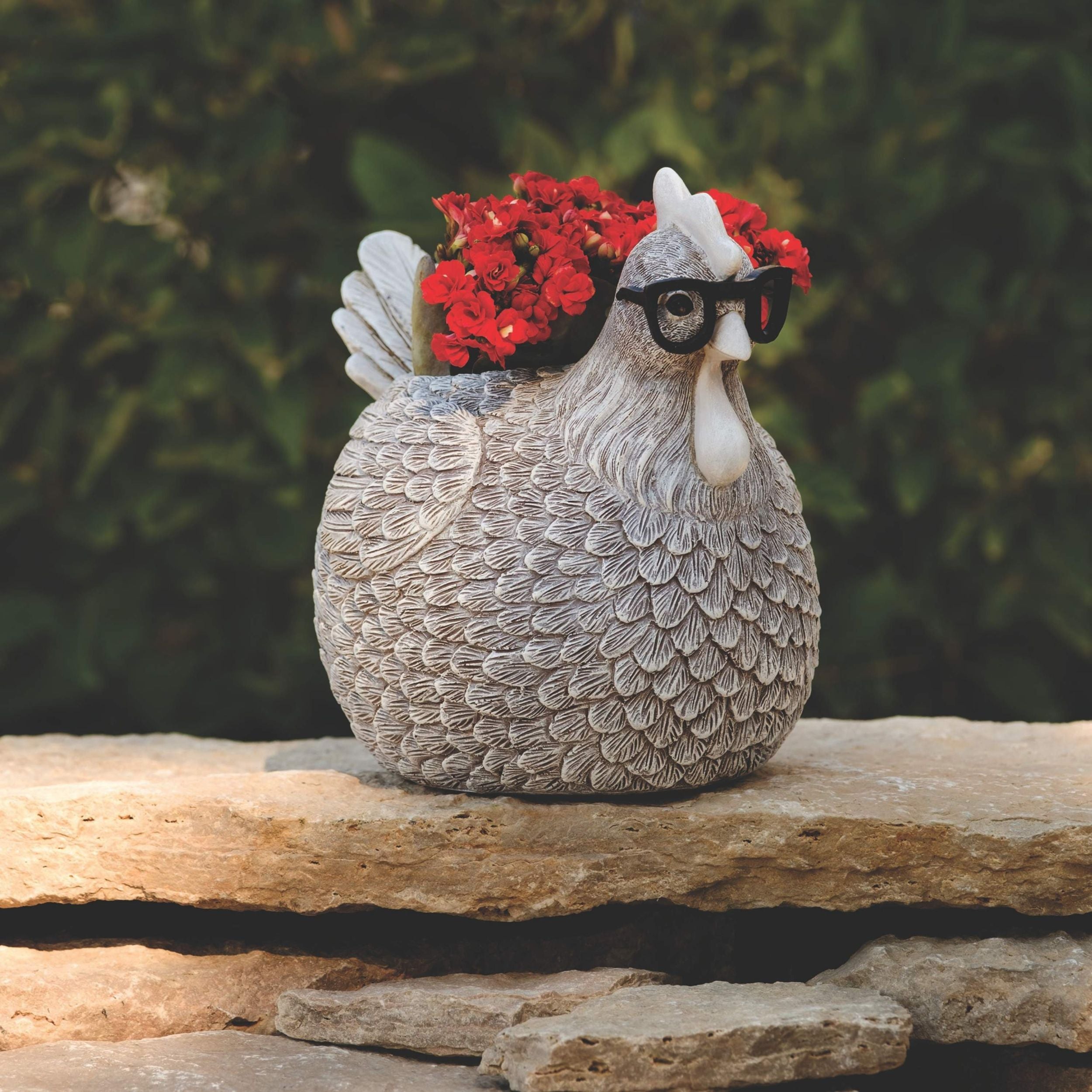 Decorative chicken statue with sunglasses and flowers on a stone surface