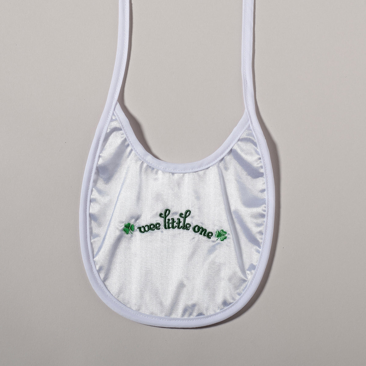 White baptism baby bib with green shamrock detailing and “wee little one” embroidery