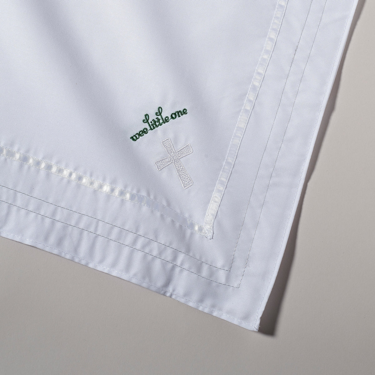 Close-up of Irish Baptism Blanket showing the embroidered cross, green shamrock accent, and decorative white border