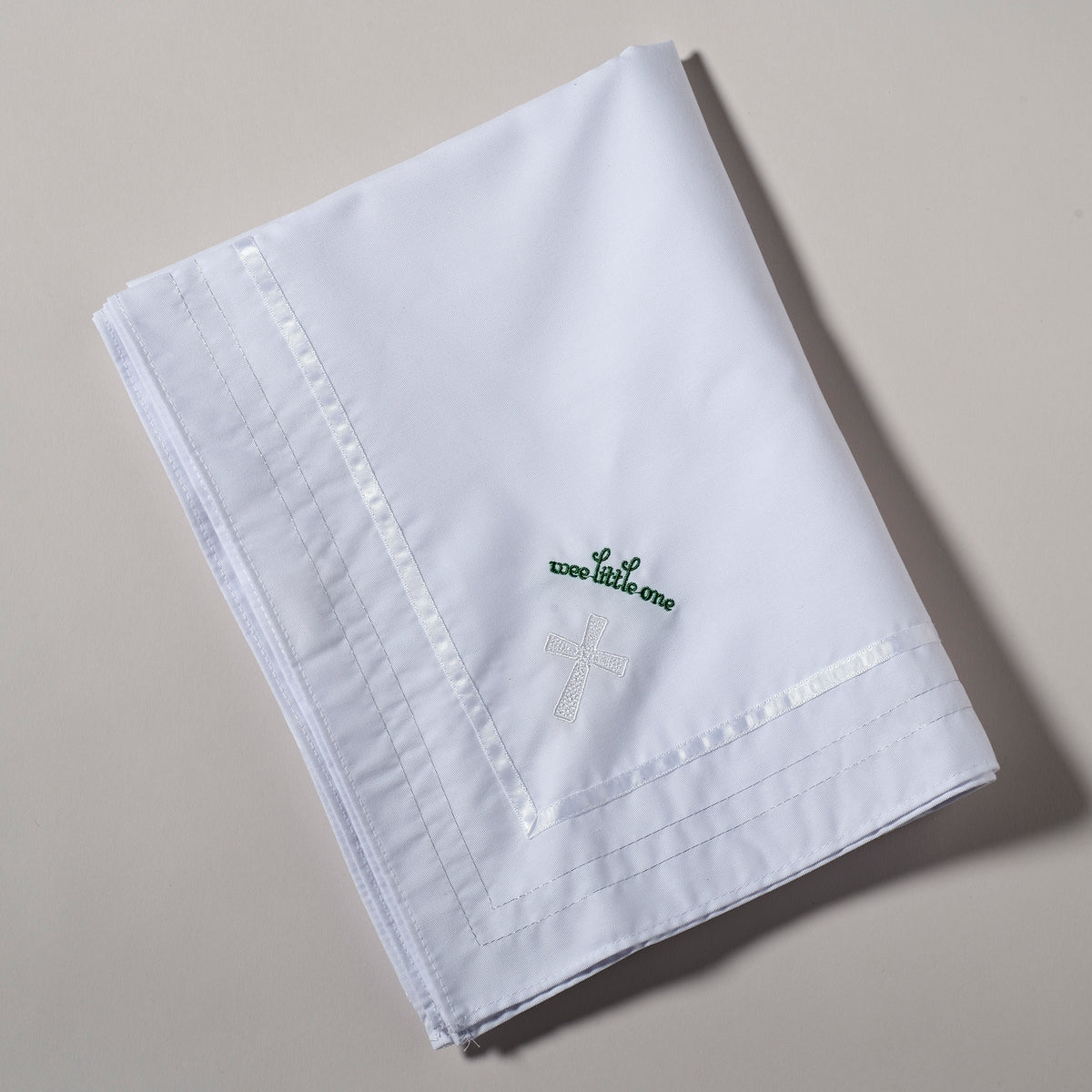 Folded Irish Baptism Blanket showing the green shamrock and cross embroidery on the soft white fabric
