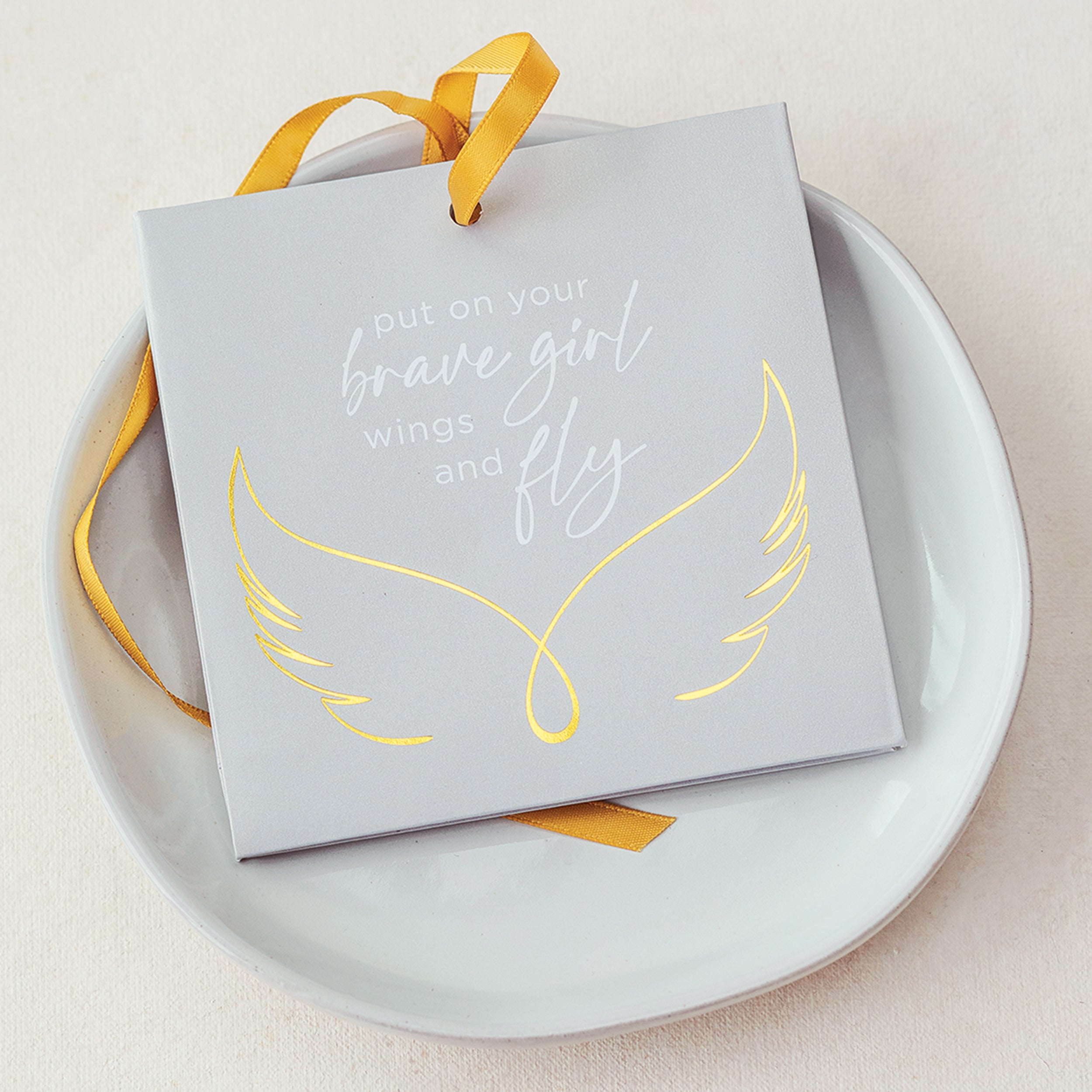 Motivational card with yellow wings and text on a white plate