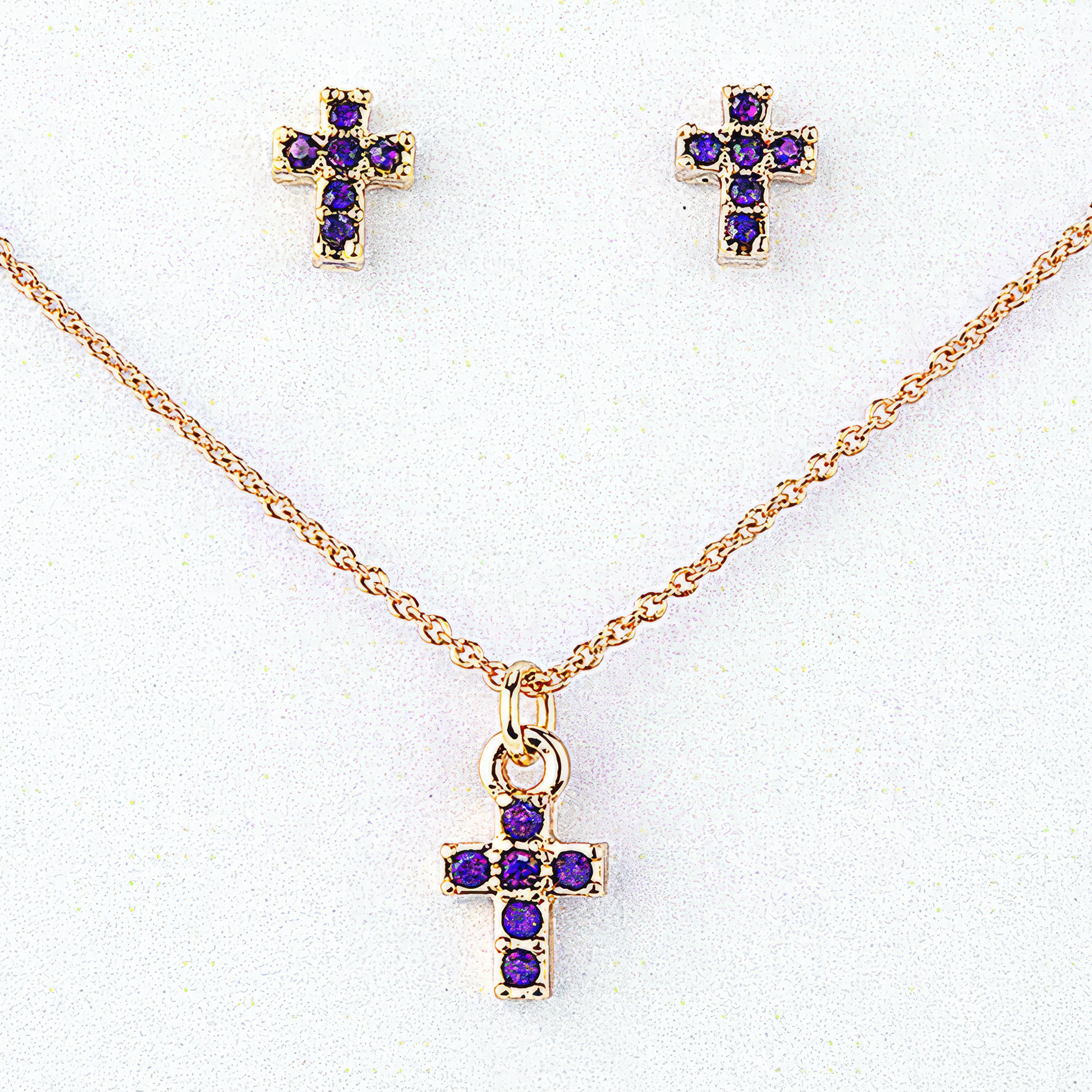 Gold cross necklace and earrings with purple gemstones on a white background