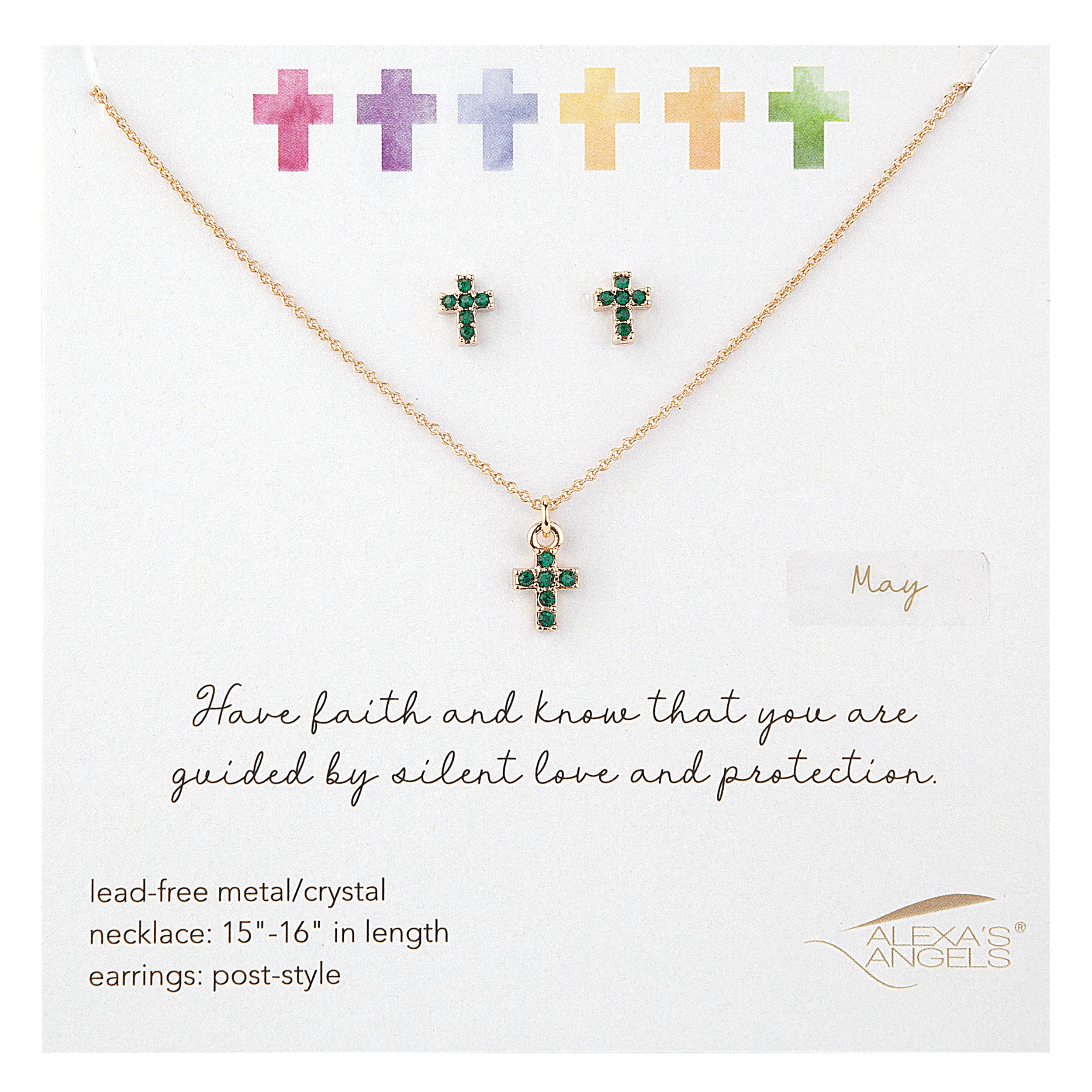 Gold necklace with green gemstone cross pendant on a white card with colorful crosses above.