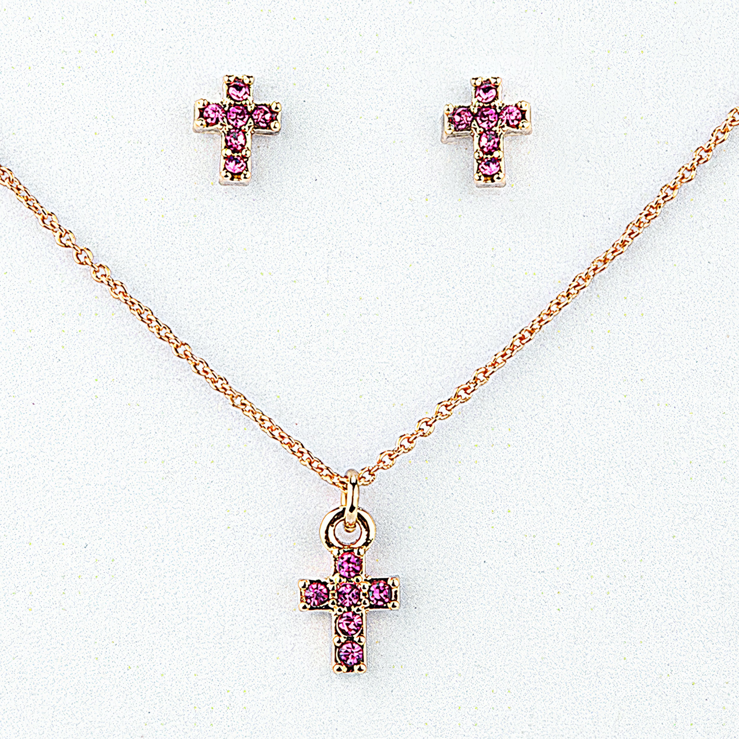 Gold cross necklace and earrings with pink gemstones on a white background