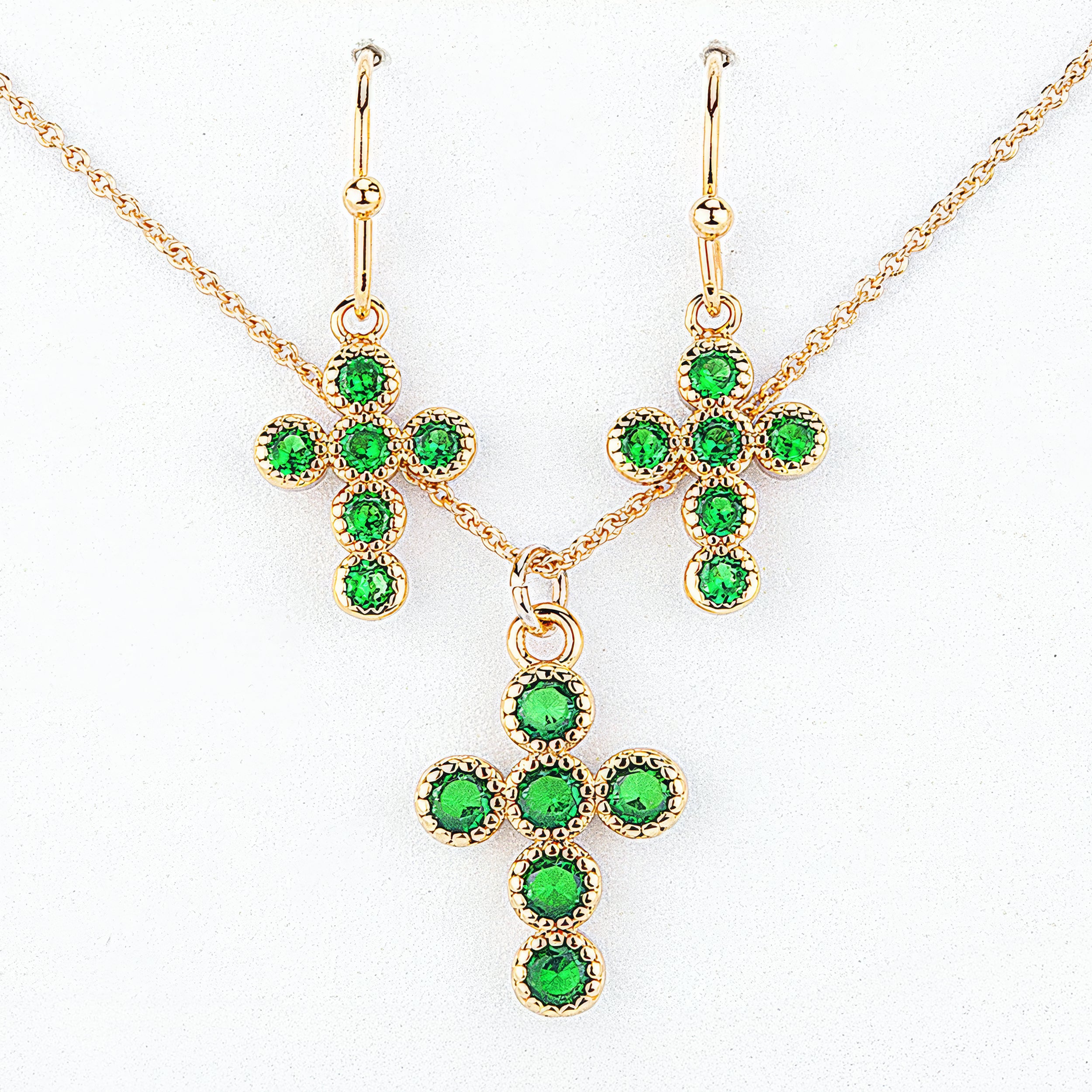 Gold jewelry set with green gemstones on a white background