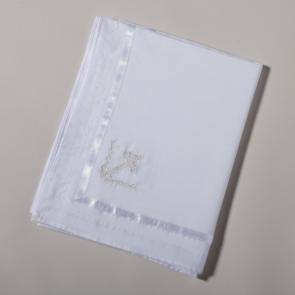 Folded White Baptism Blanket showing the embroidered cross design and neatly finished white border