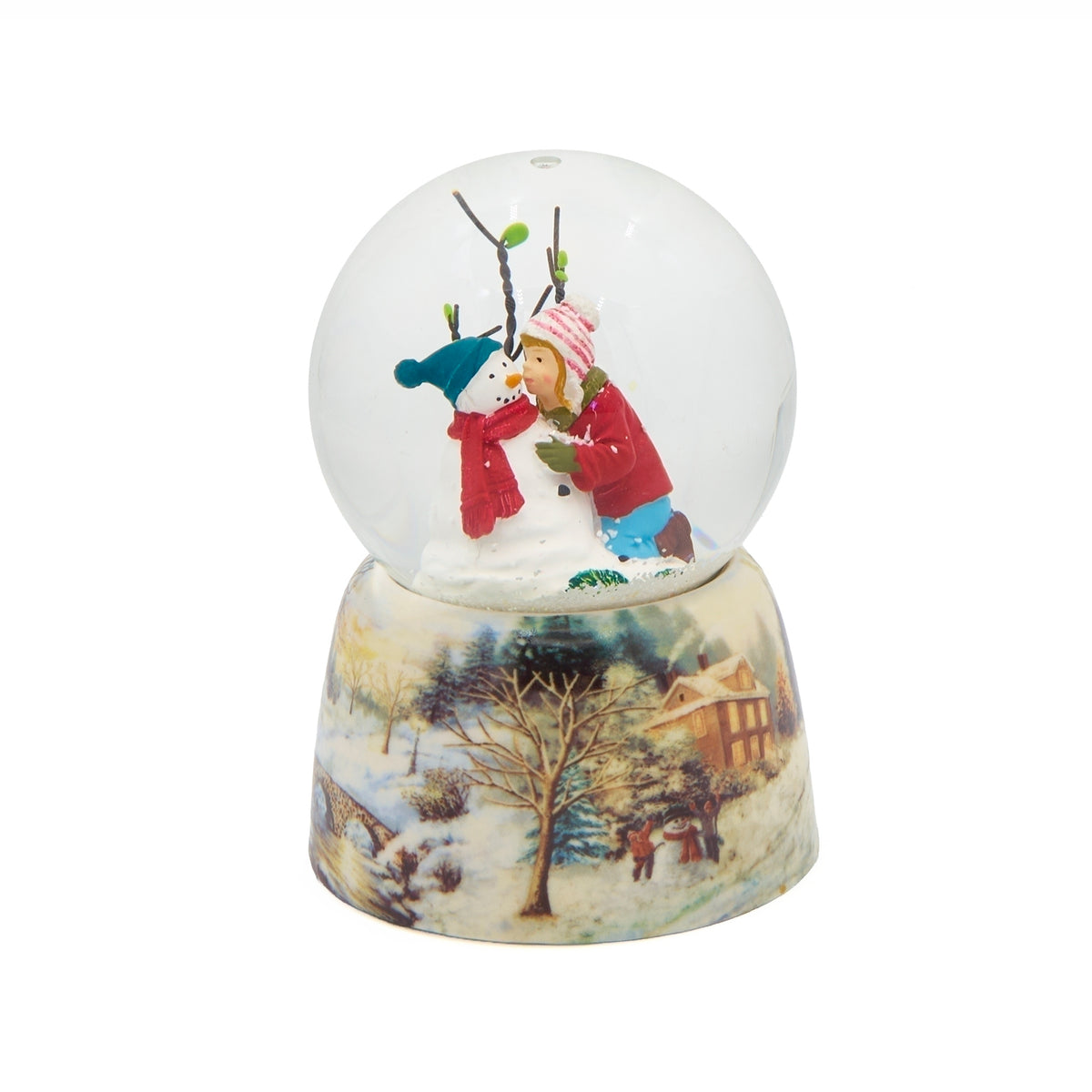 Angled view of A Kiss for Frosty snow globe showing the snowman’s blue hat and red scarf beneath bare winter branches.