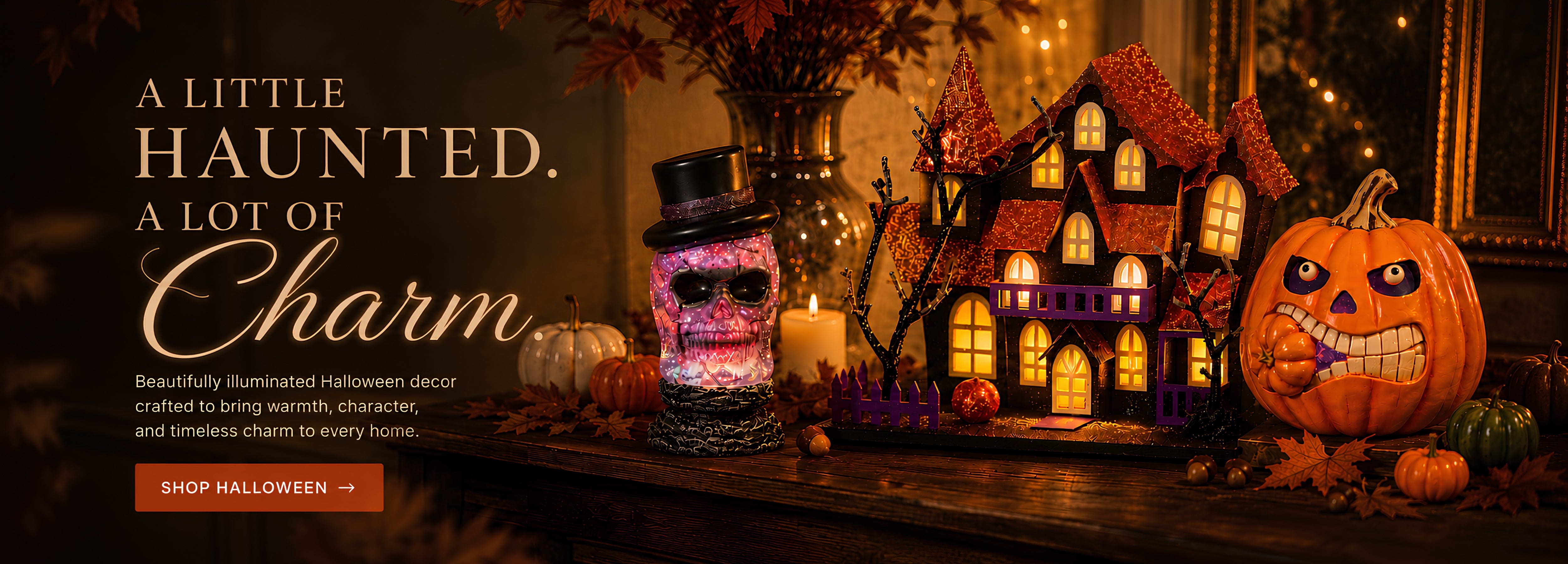 Halloween-themed promotional scene with a carved jack-o'-lantern, a haunted house decoration, candles, and a small decorative jar on a wooden surface. Large text reads 'A LITTLE HAUNTED. A LOT OF CHARM' with a shop halloween button.