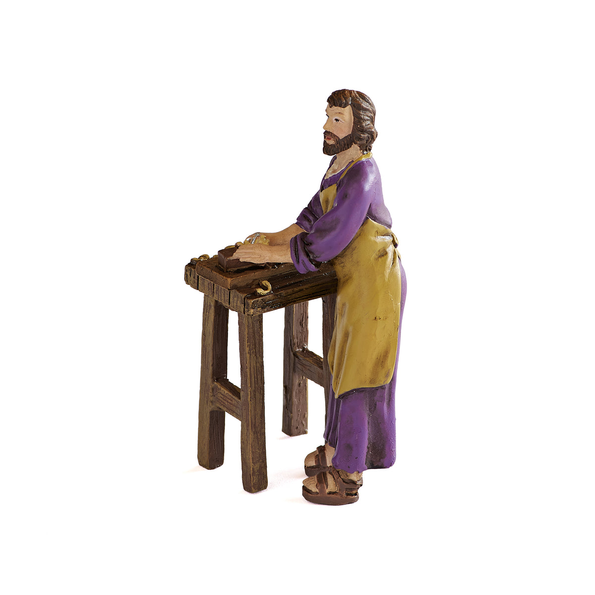 Side view of St. Joseph the Worker figure showing the saint working at a wooden carpenter bench