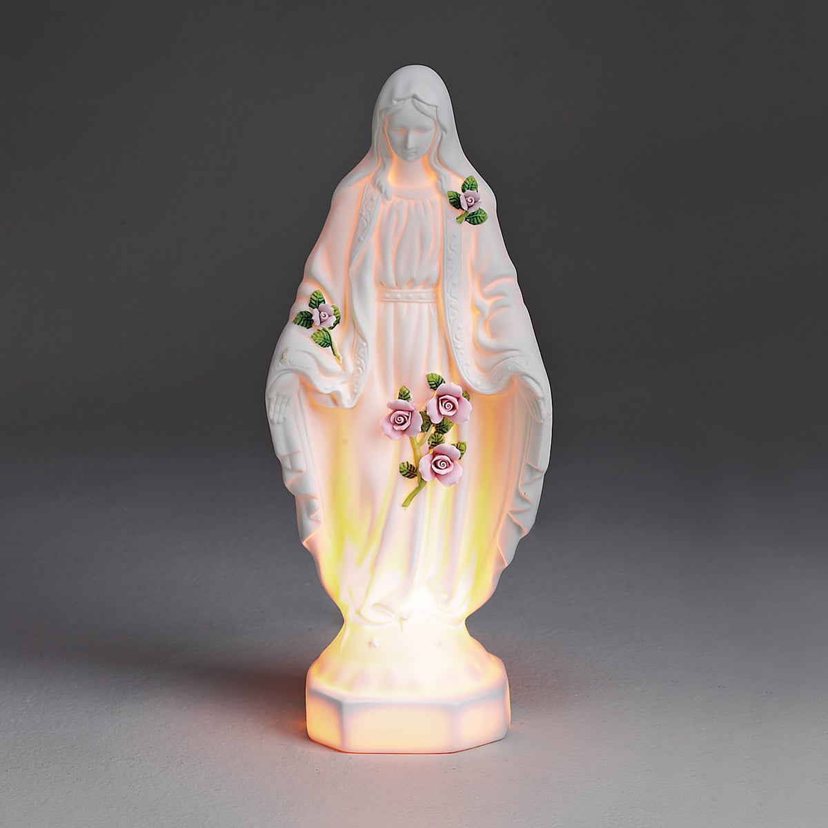 Illuminated view of Our Lady of Grace figure glowing warmly with soft pink and gold light