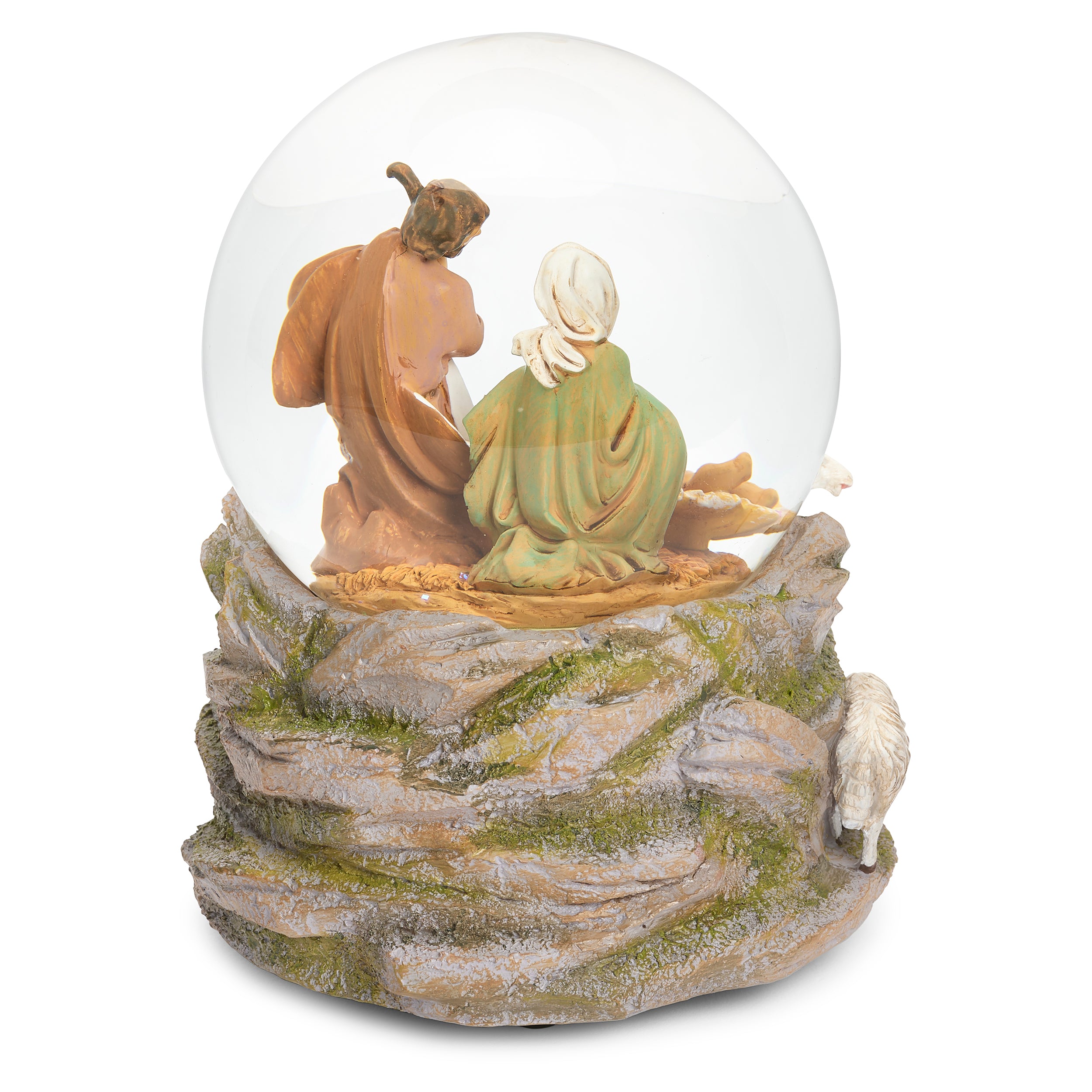 A nativity-themed snow globe figurine featuring Mary and Joseph seated inside a clear glass globe, with a rocky base detailed with green moss and a small white sheep on the right, shown on a plain white background.