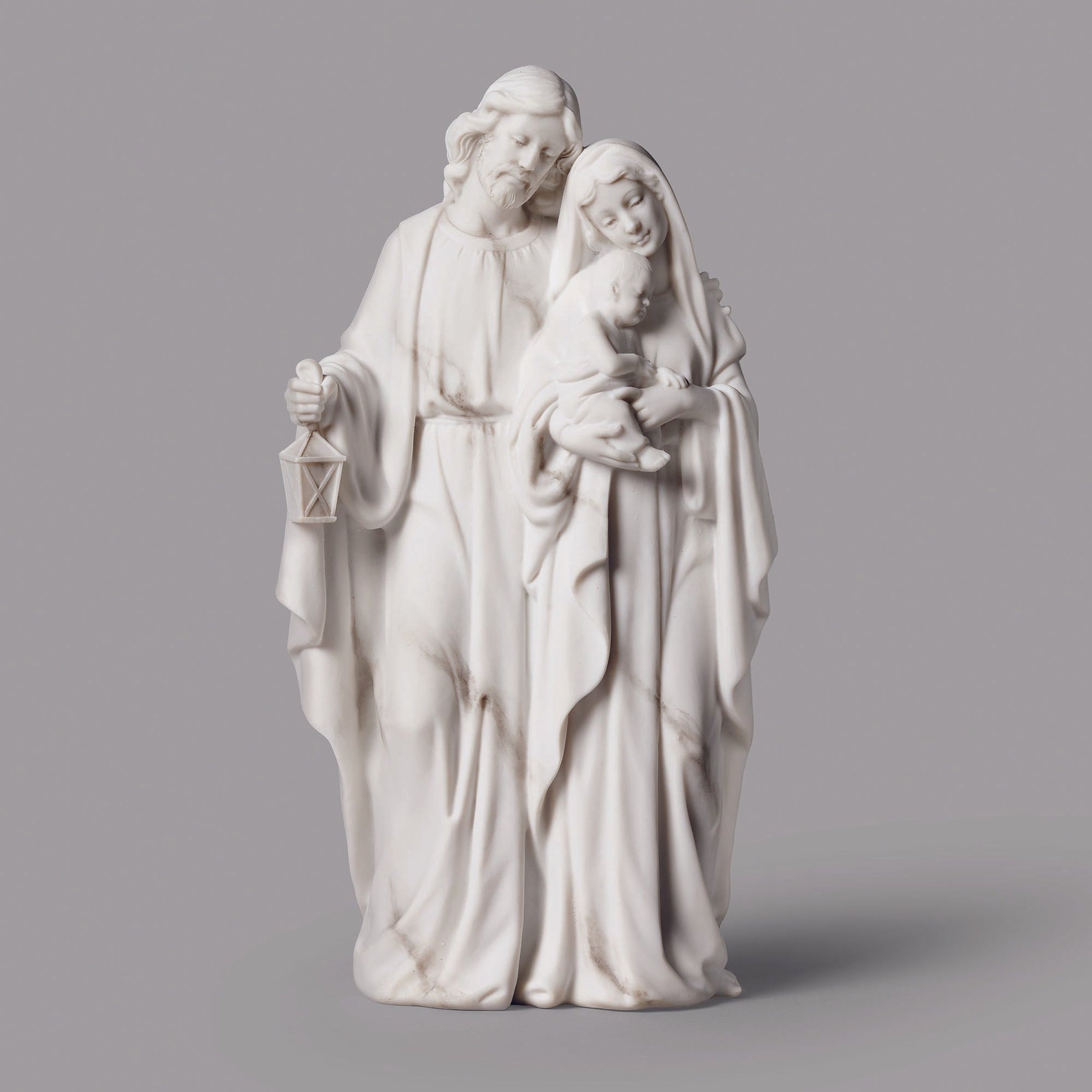 White ceramic statue of a couple holding a child on a gray background