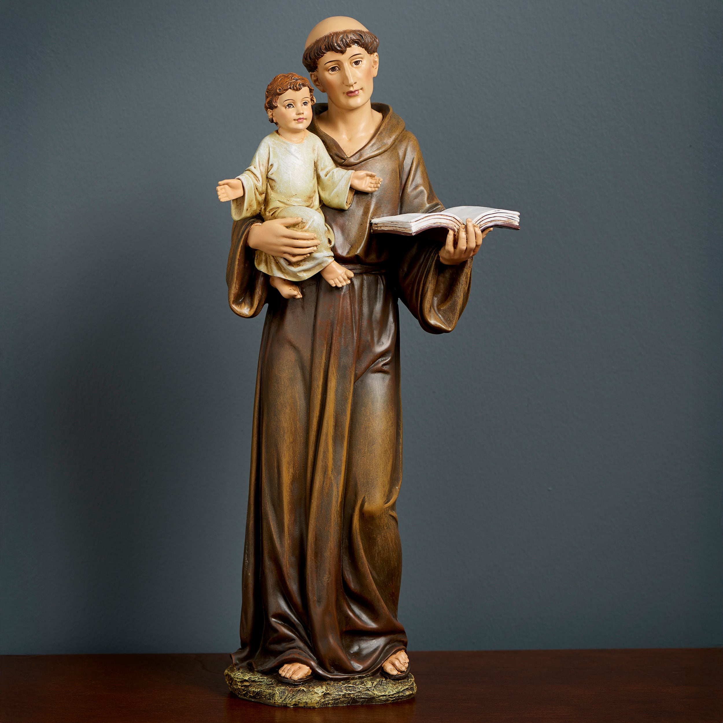 Statue of a religious figure holding a child and an open book against a dark background