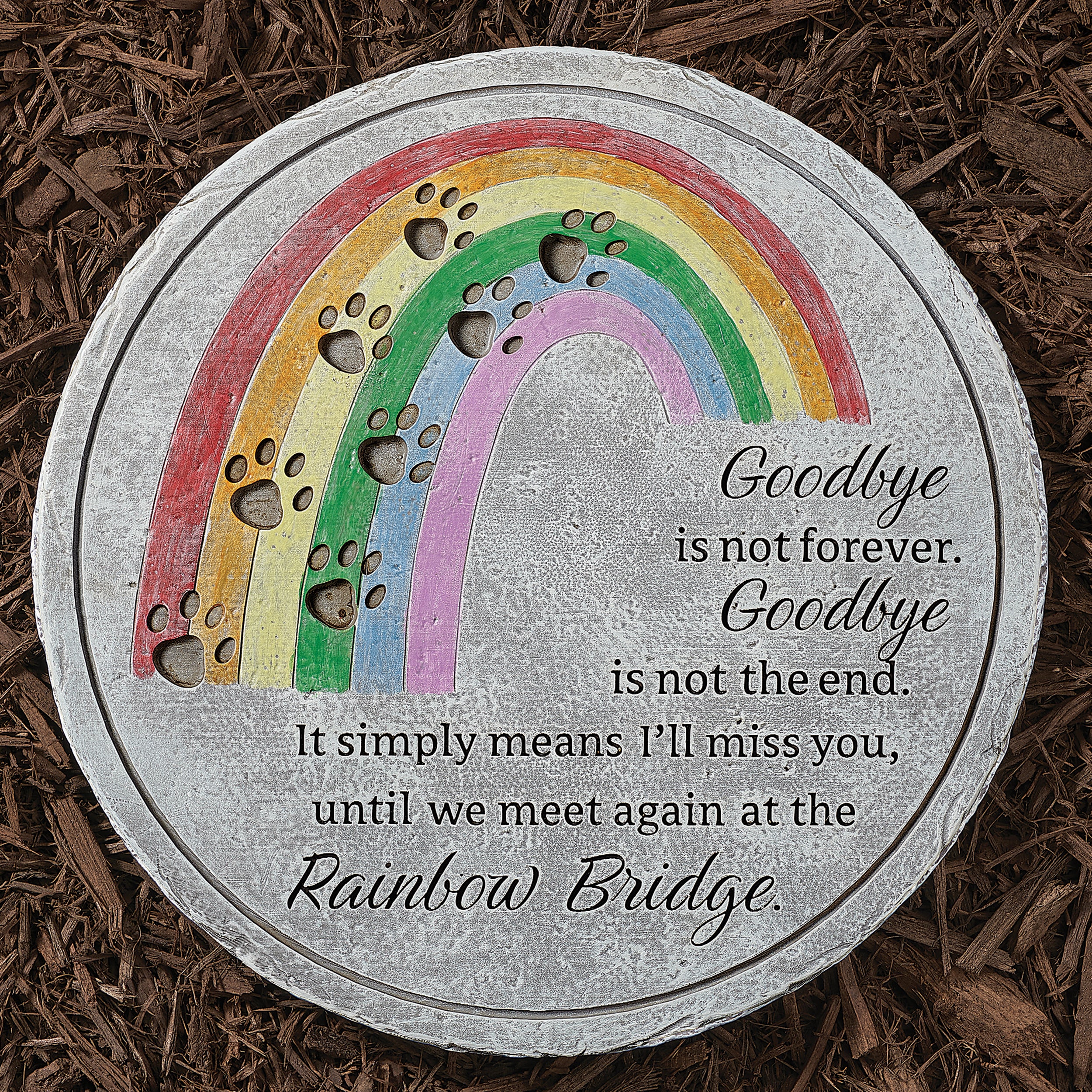 Memorial plaque with rainbow design and text on a brown mulch background