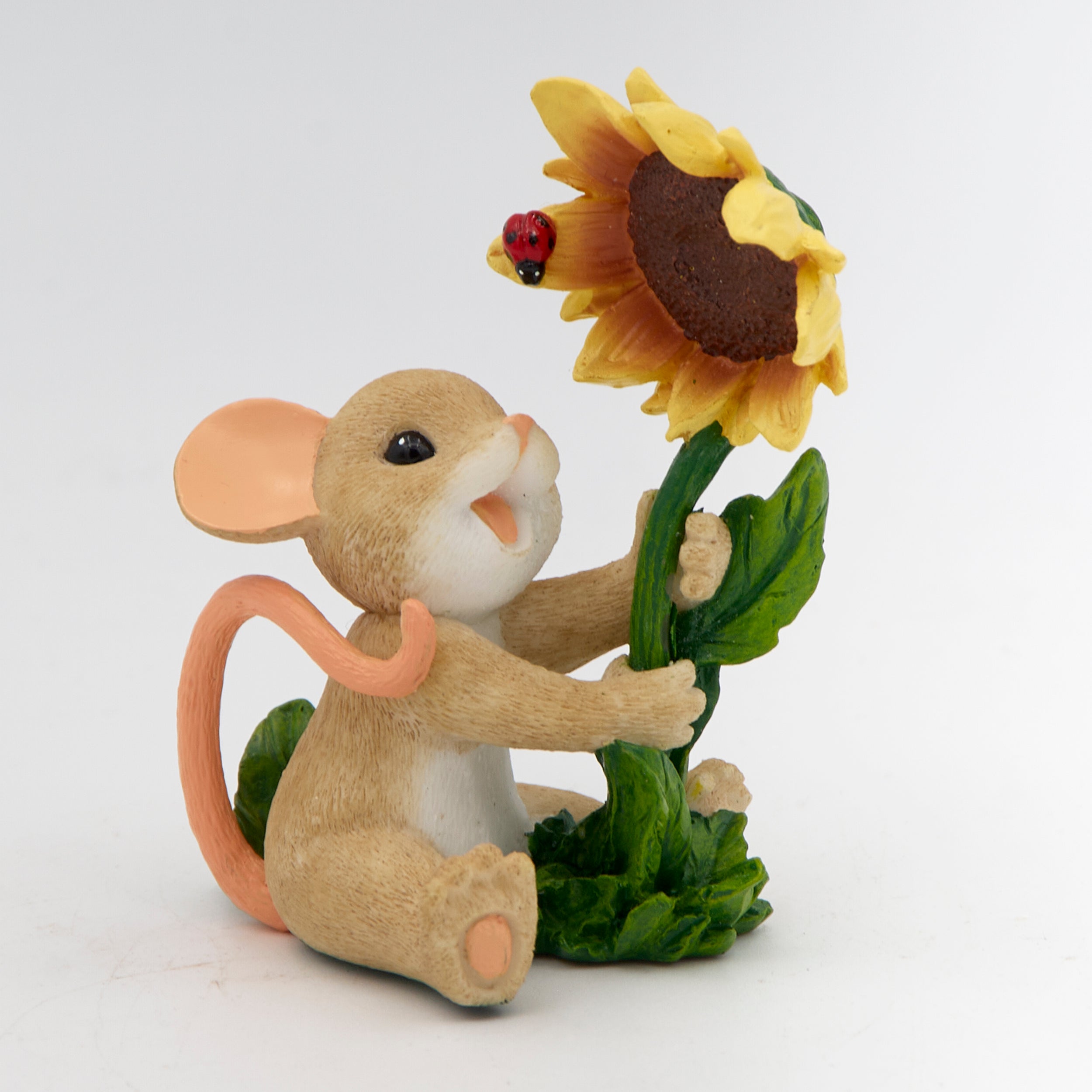 Mouse figurine holding a sunflower with a ladybug on a white background