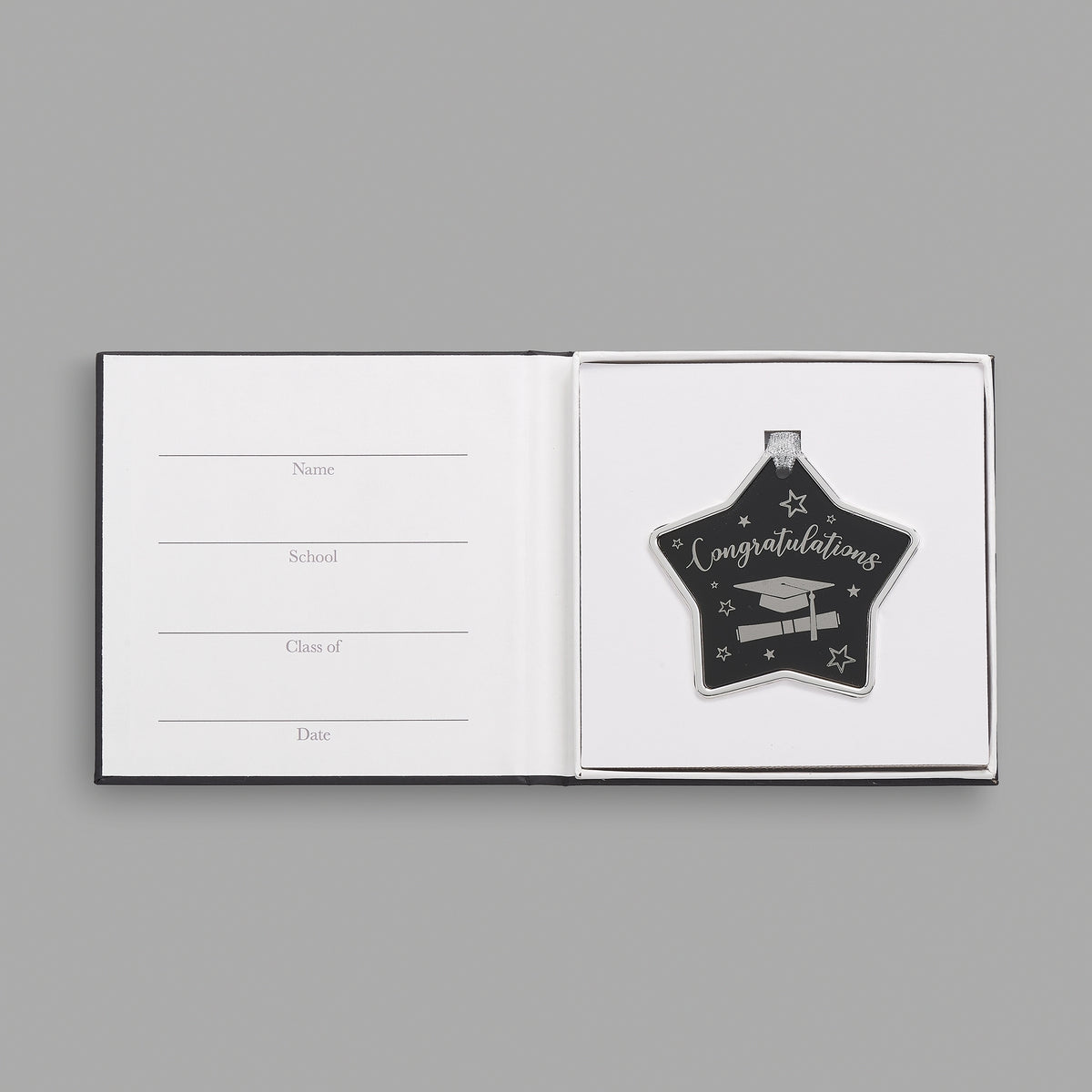 Open keepsake packaging displaying the black graduation star ornament beside a printed message.