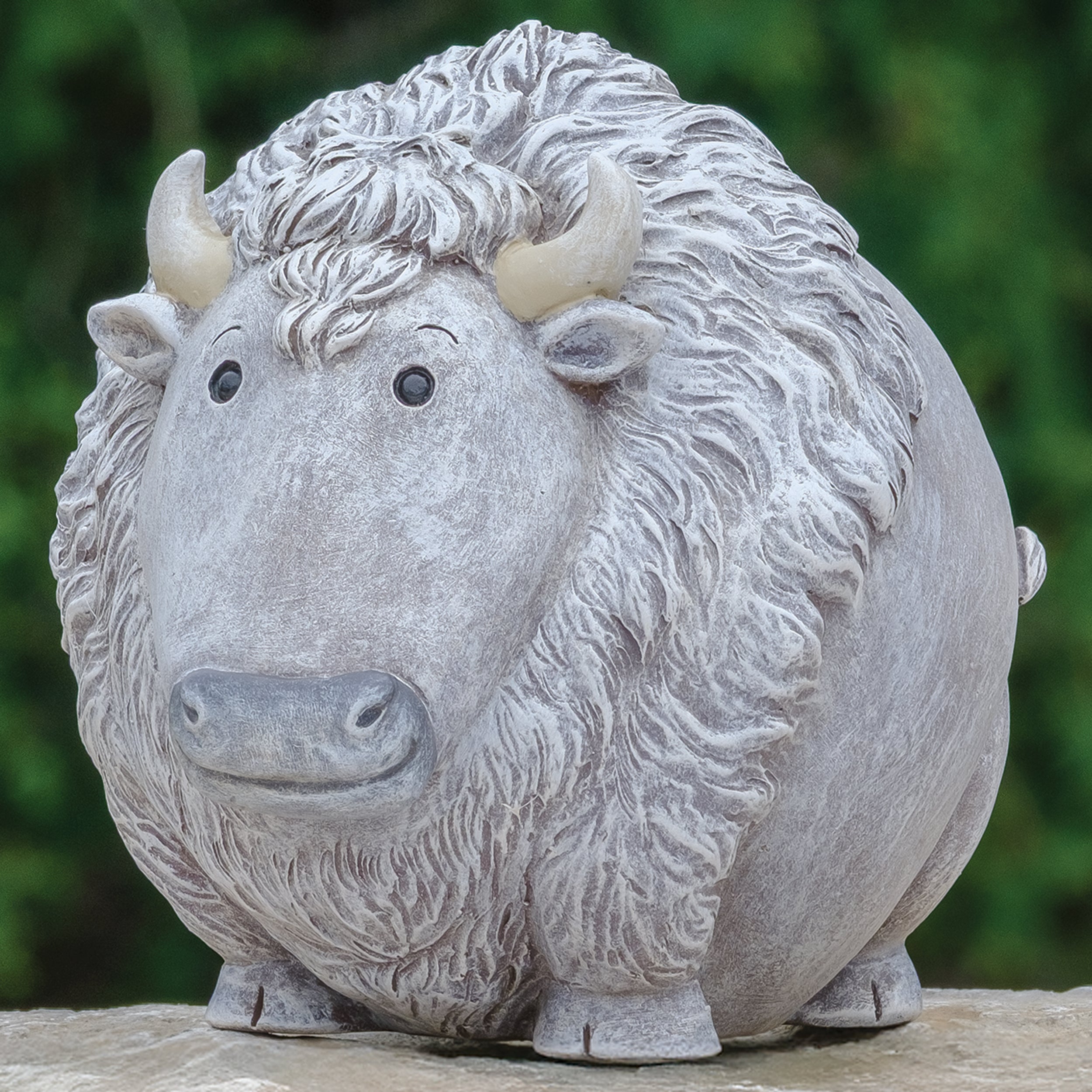 Stone sculpture of a bison with a textured surface against a blurred green background
