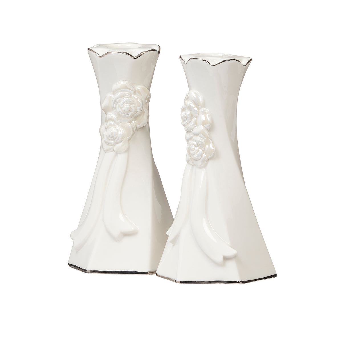Two white porcelain taper holders with raised floral and ribbon designs and flared bases.