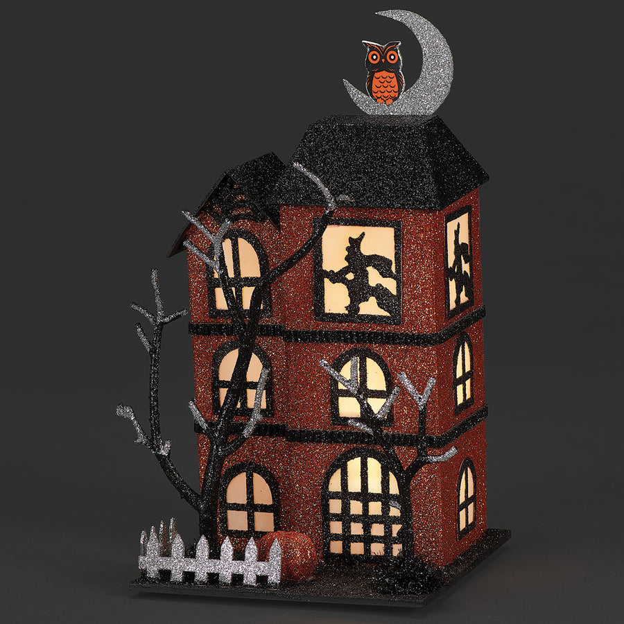 Halloween-themed decorative house with glowing windows and an owl on a crescent moon.