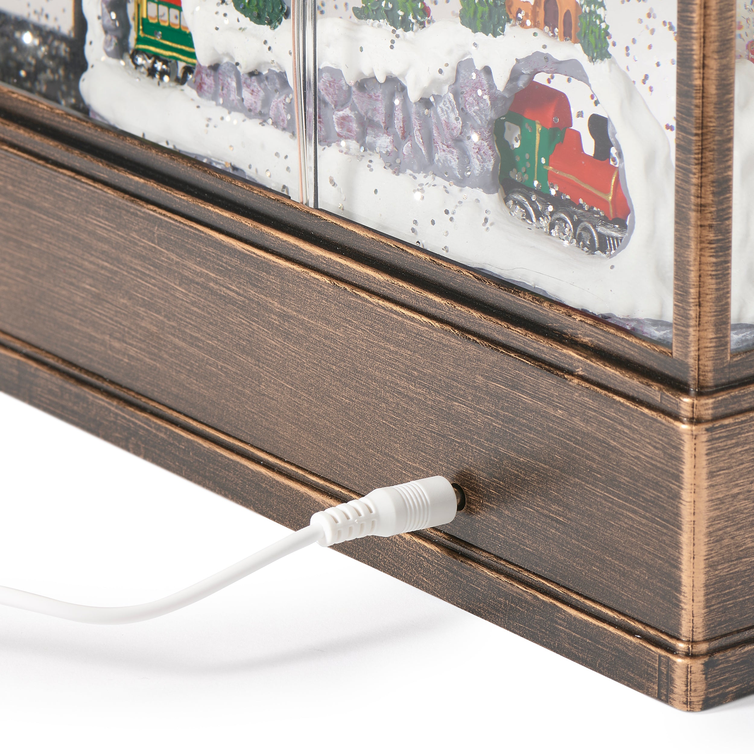 Close-up of a wooden box with a white cable plugged into it, featuring a miniature train scene inside.