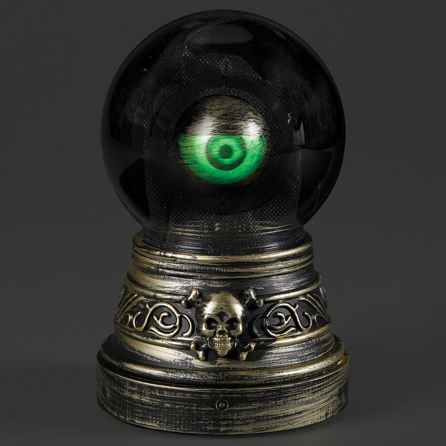 Black crystal ball with a green eye on a decorative metal stand against a dark background