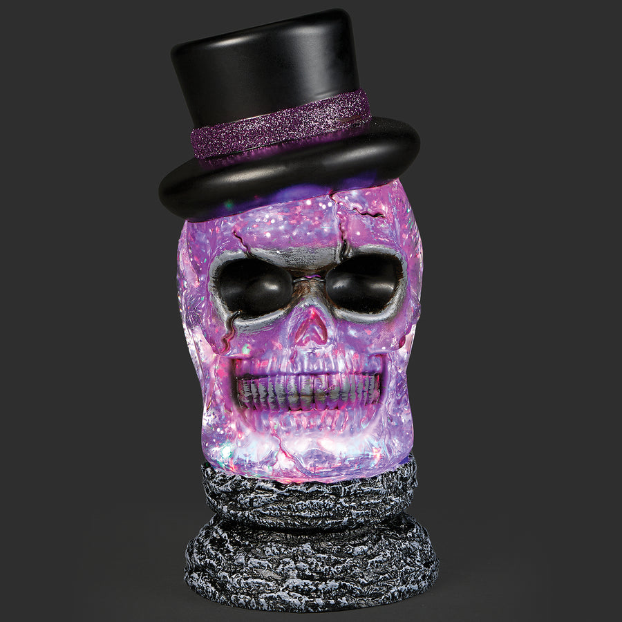 Decorative skull with a black top hat and purple glittery finish on a dark background