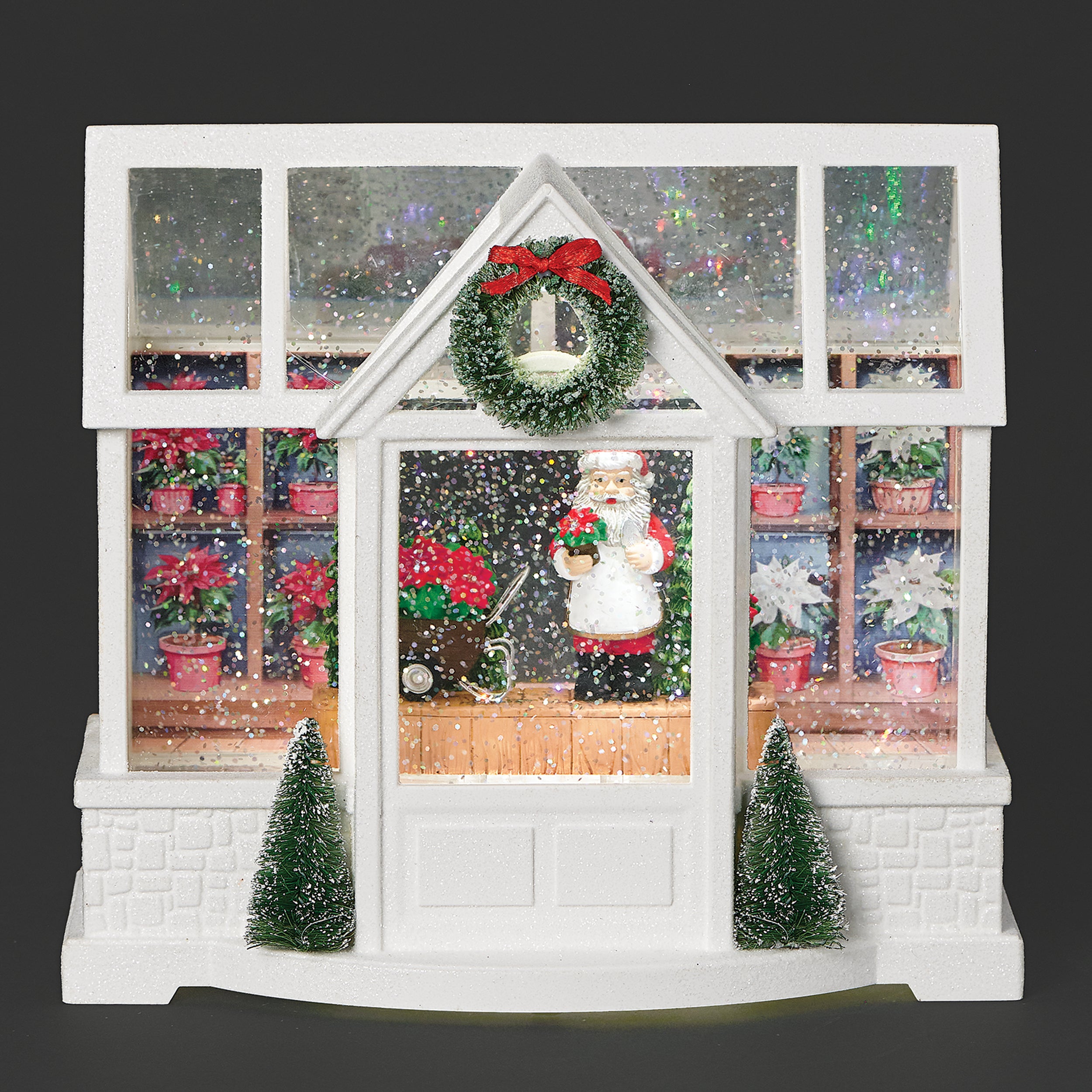 Decorative Christmas scene with Santa Claus inside a white house model, surrounded by festive decorations.