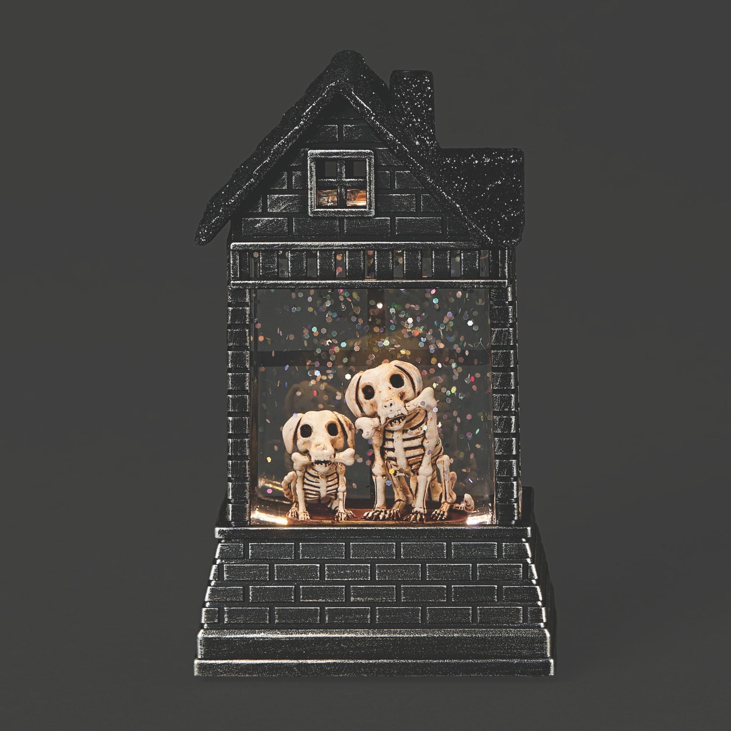 Decorative house-shaped light with skeleton dog figures on a dark background