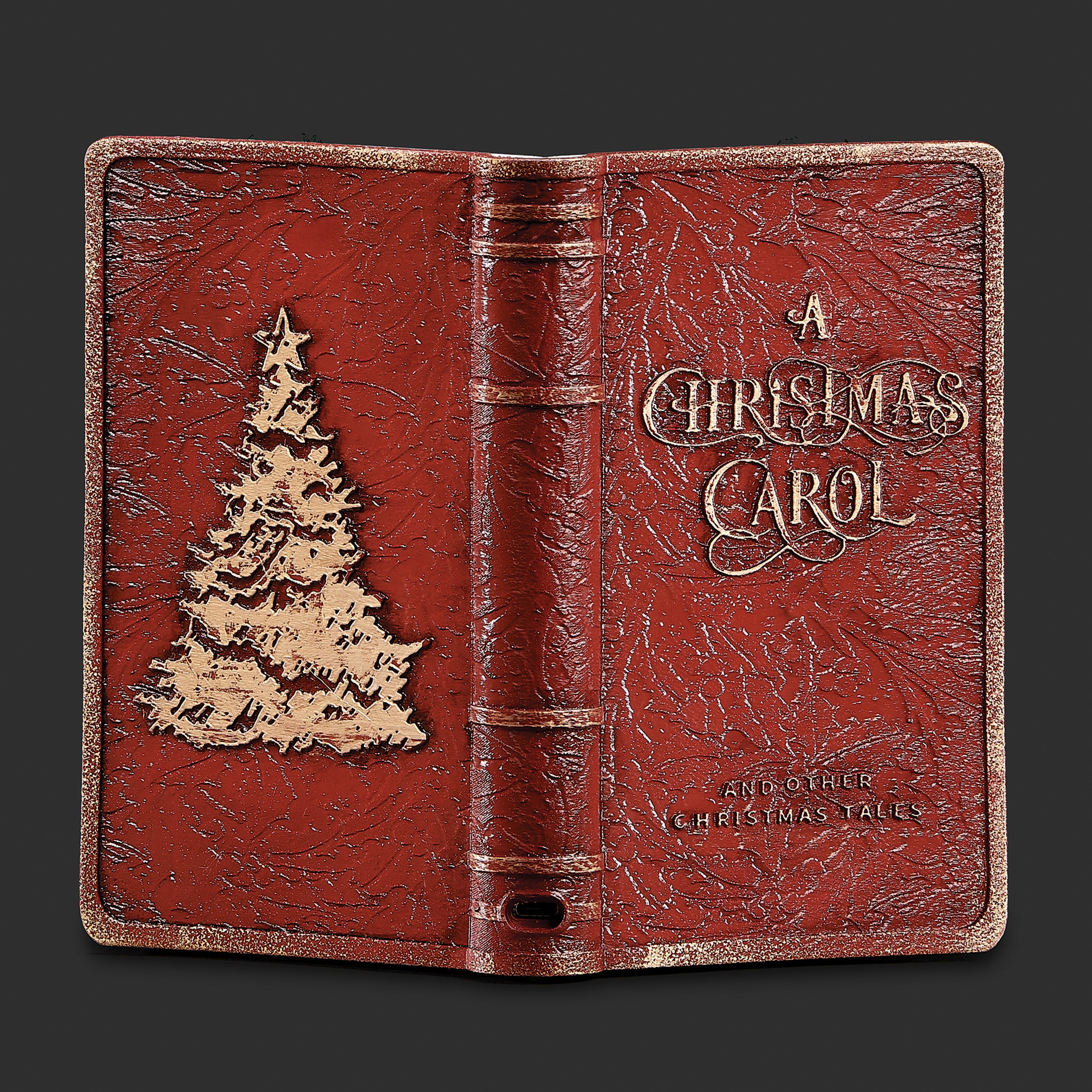 Red leather-like book titled 'A Christmas Carol' with a Christmas tree design on a dark background
