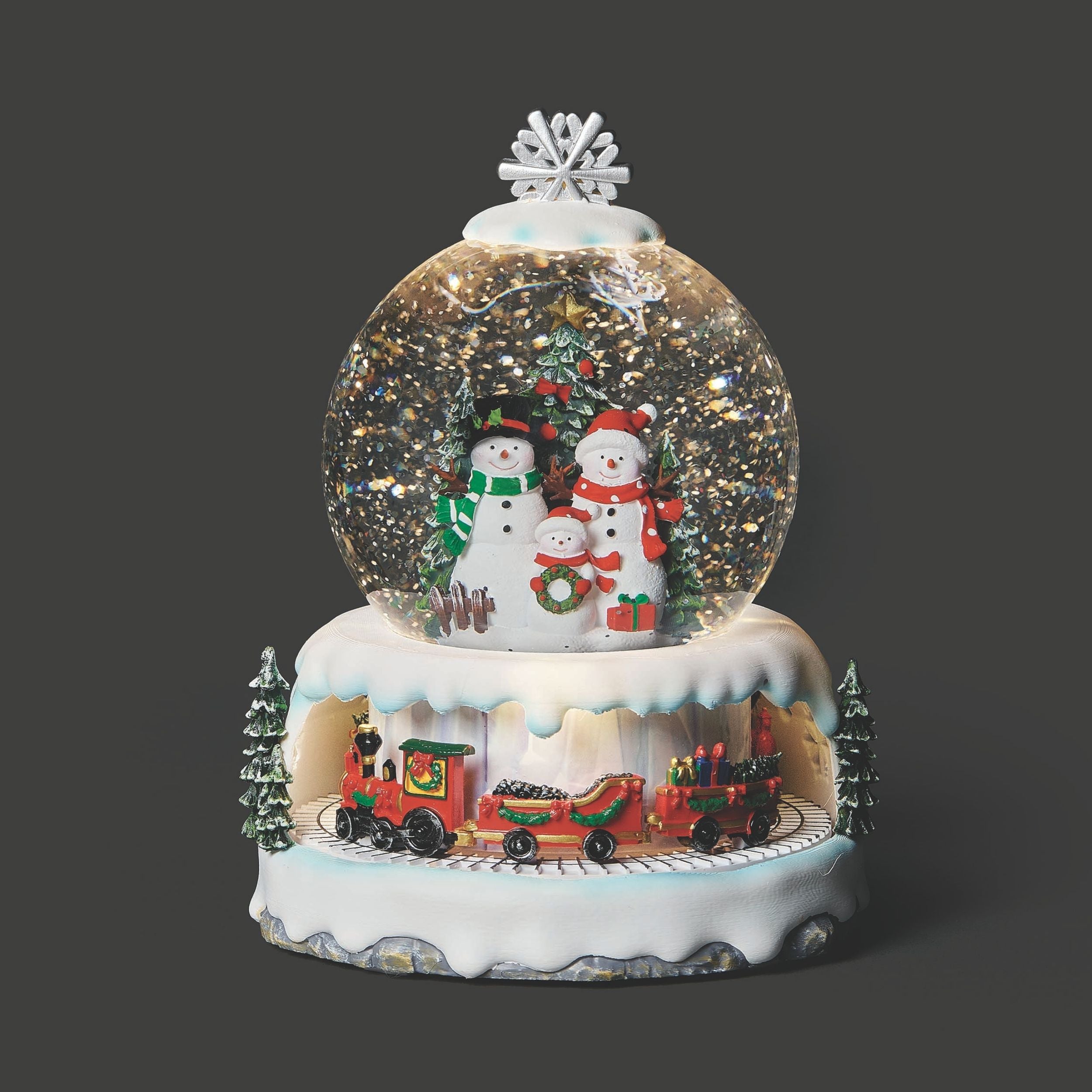 Christmas-themed snow globe with snowmen, a train, and trees on a dark background