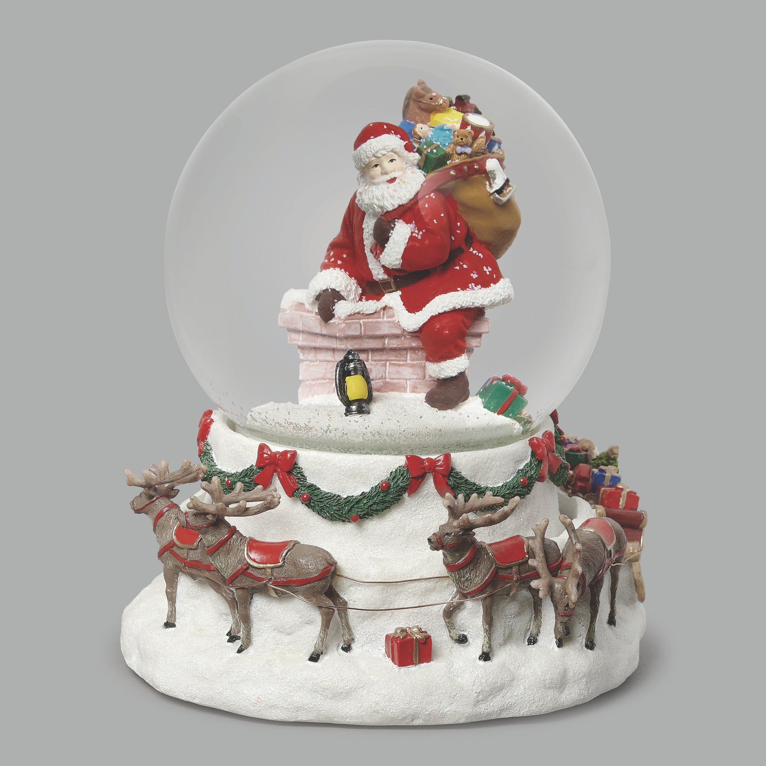 Christmas snow globe with Santa Claus on a roof, reindeer, and presents.