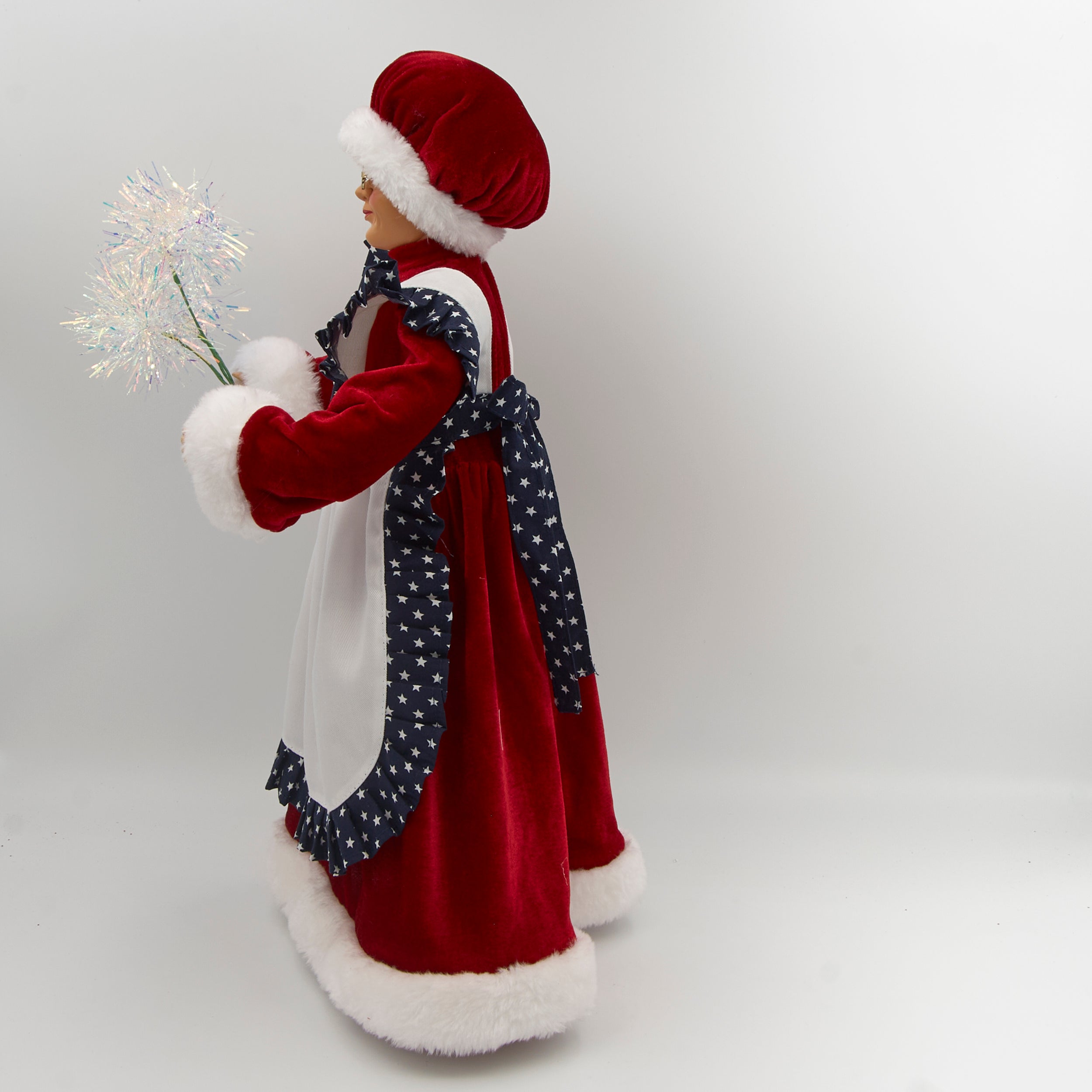 Decorative figure of a woman in a traditional outfit with a white apron and red hat, holding sparklers on a white background.